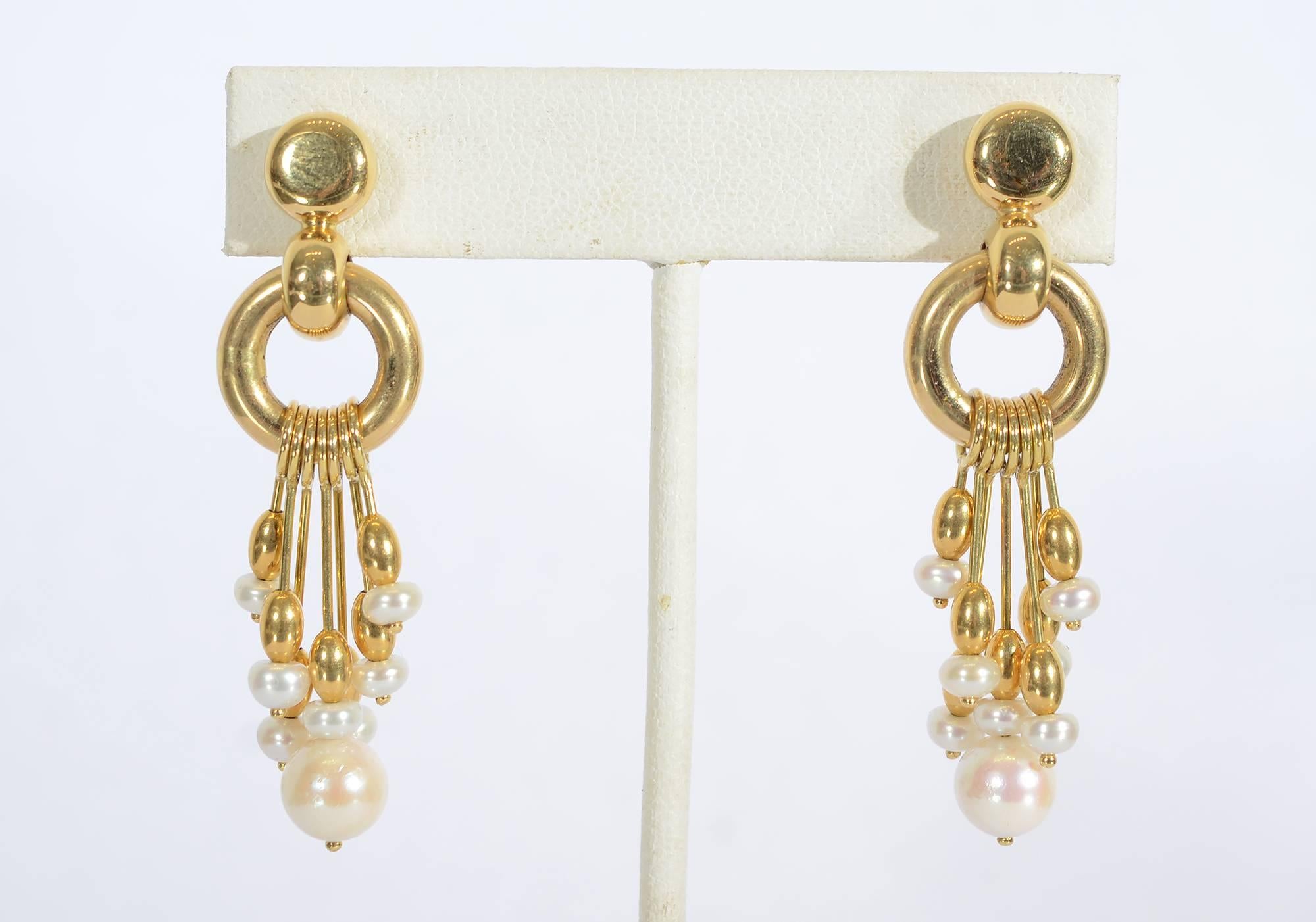 Pearls are suspended on spokes in these unusual dangle earrings. A gold circle 1/2