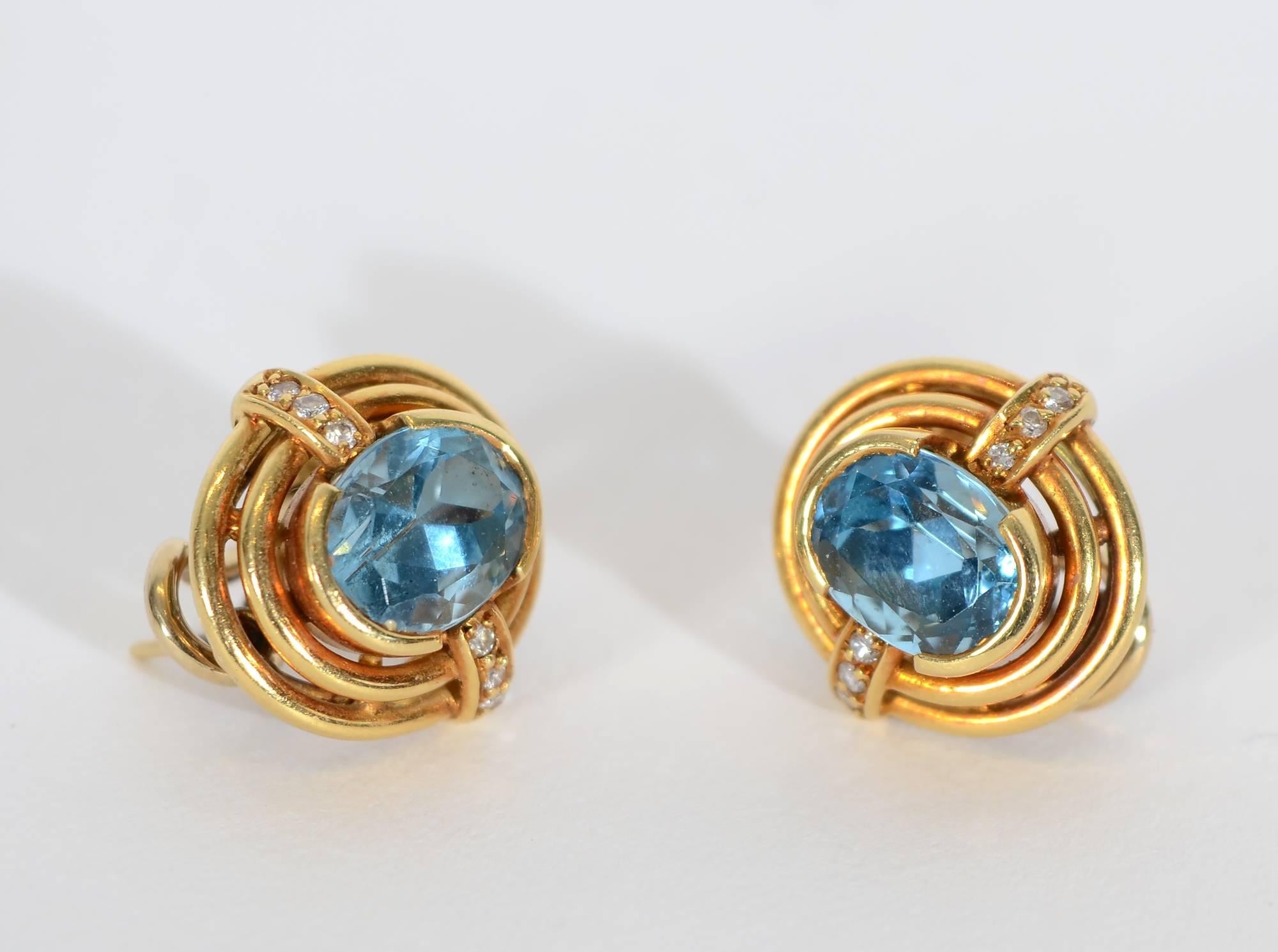 H. Stern earrings that are tailored yet have a hint of bling. The center stone is blue topaz surrounded by 3 small diamonds on either side. Three oval tiers of gold and a collar set center stone give nice dimensionality. Post and clip backs.