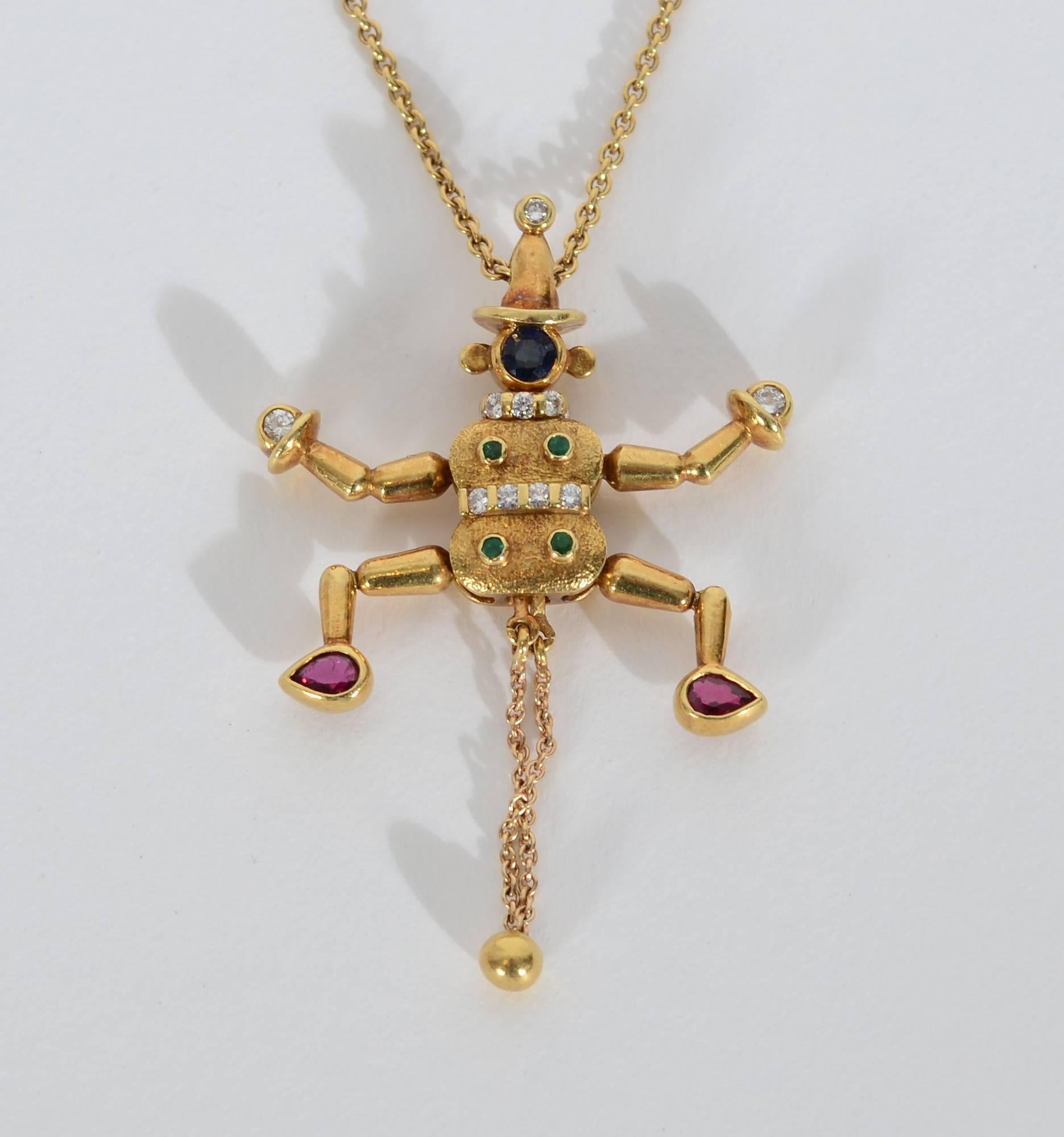 This whimsical clown pendant moves his arms and legs when one pulls the chain beneath him. The clown has a blue sapphire face; ruby feet; diamond hands, belt and neck collar and emeralds on his body. He is strung on a 15 1/2 inch chain of 18 karat