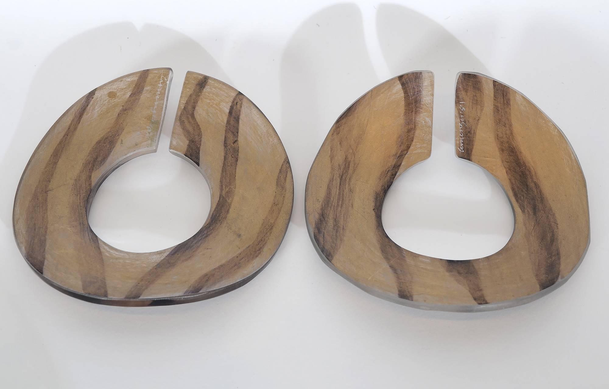 This pair of undulating lucite bracelets were made early in the career of noted American jewelry designer, Angela Cummings. One is matte on both sides and the other is gloss on one and matte on the other. Both are decorated with tiger stripes.   The