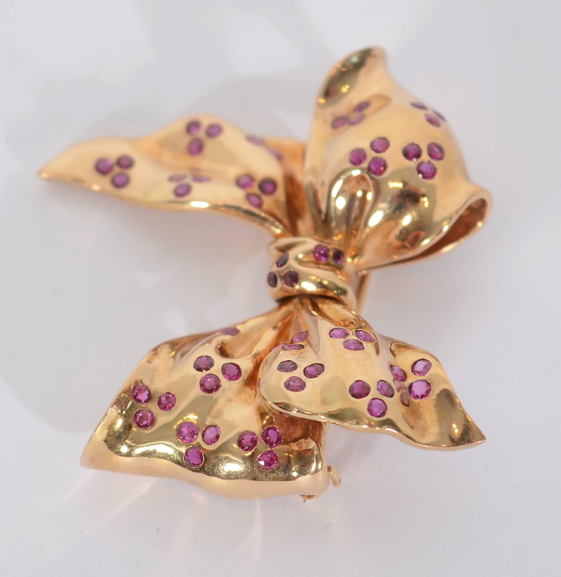 Beautifully made Retro Bow Brooch with trios of Burmese rubies. The metal is worked to very effectively have the appearance of fabric. The brooch measures 2 inches wide and 1 3/4 inches tall.