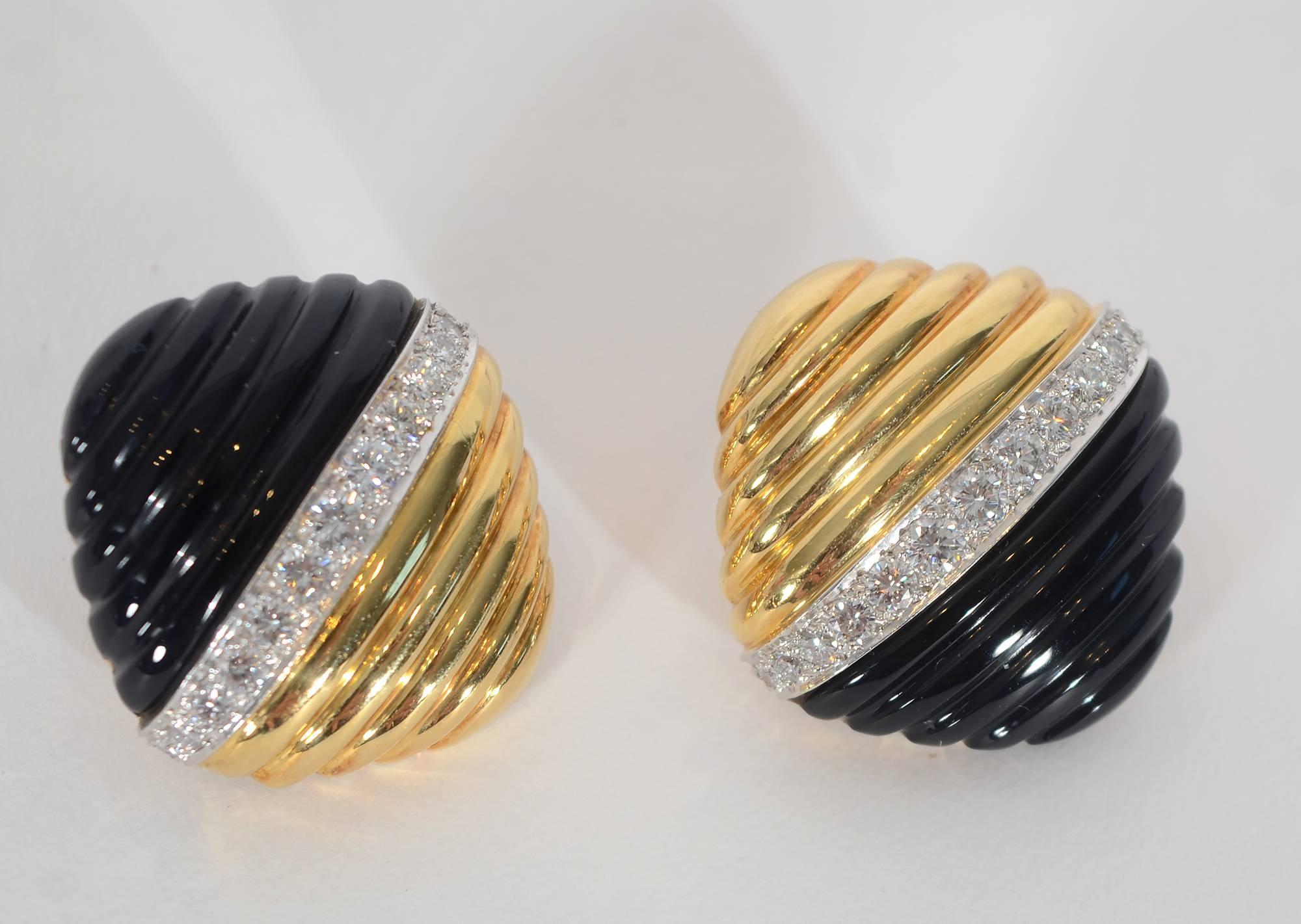 Striking earrings by Trianon with half in ribbed gold and the other half mirroring the ribbed pattern with carved onyx. Separating the two materials is a row of VS 1 diamonds weighing a total of approximately 2.2 carats. Backs are clips. A  design