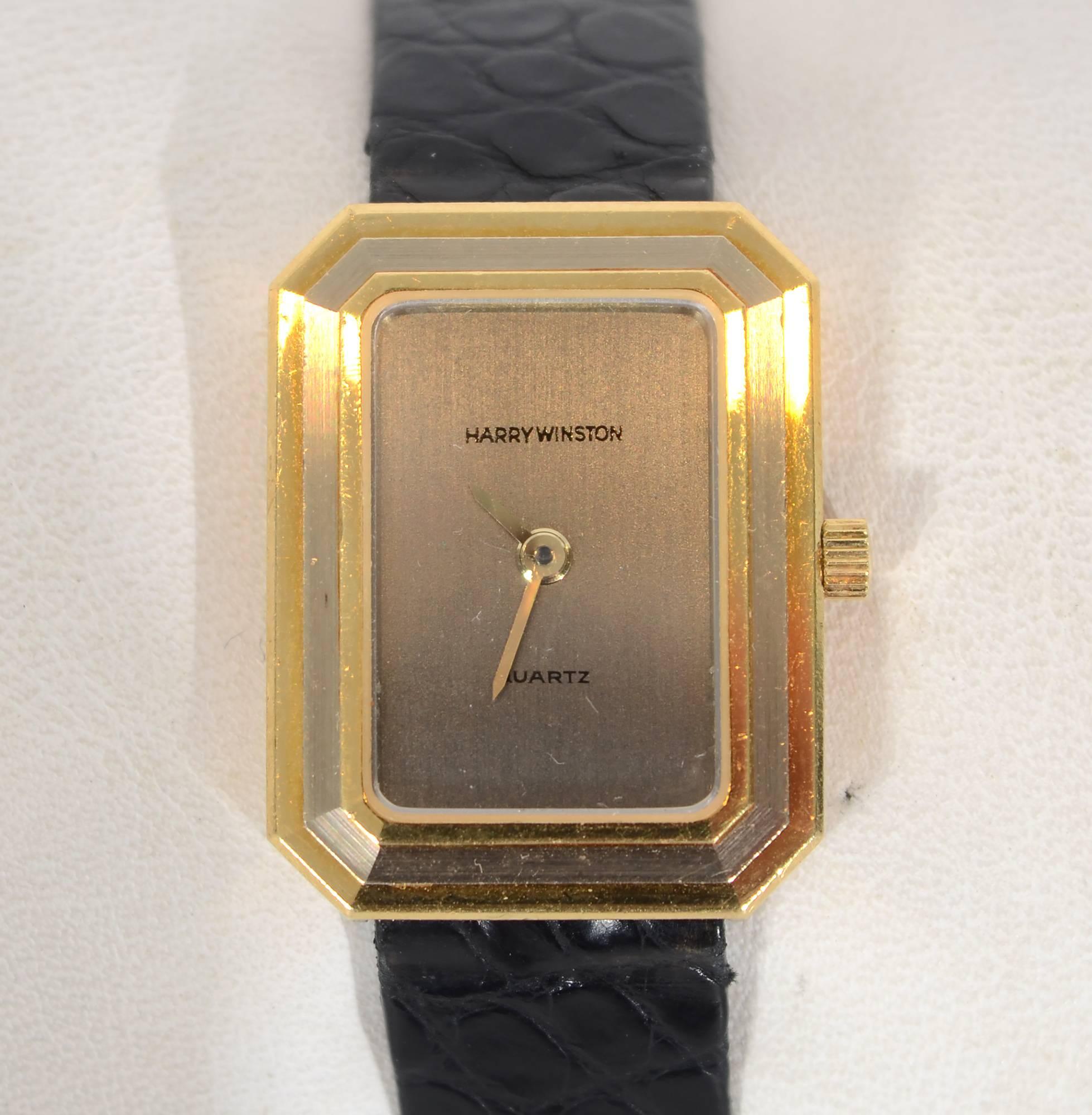 Harry Winston sporty tank wrist watch in yellow and white gold. Yellow gold outer and inner bands frame one of white gold. The face is silvertone with gold hands. The movement is quartz. The band is the original Winston strap with a buckle that