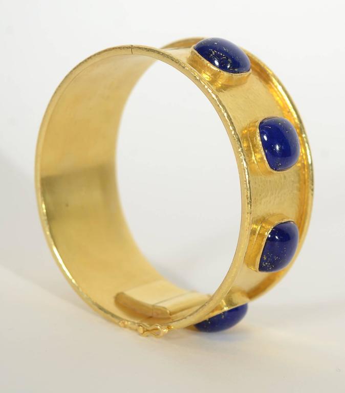 Stunning  wide gold bracelet by Elizabeth Locke with four cabochon lapis lazuli stones. The stones are all square in shape. The bracelet is made with Locke's signature hammered gold surface and finished with banded edges. It is no longer in