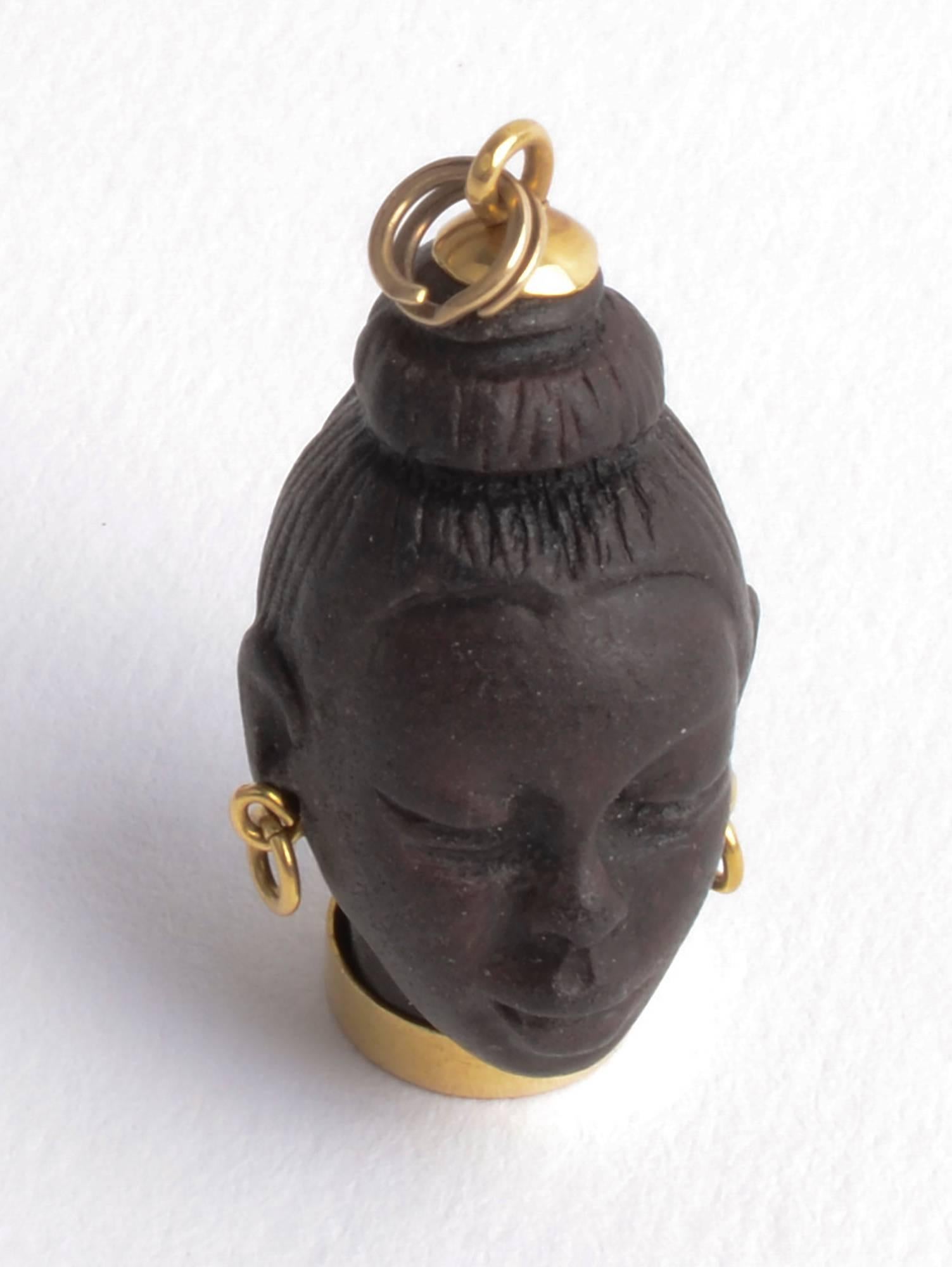 Finely carved, beautiful African female  mounted on an 18 karat gold base with gold earrings and loop for hanging. The face is probably ebony. It is carved with terrific detail to the face; ears and hair. 