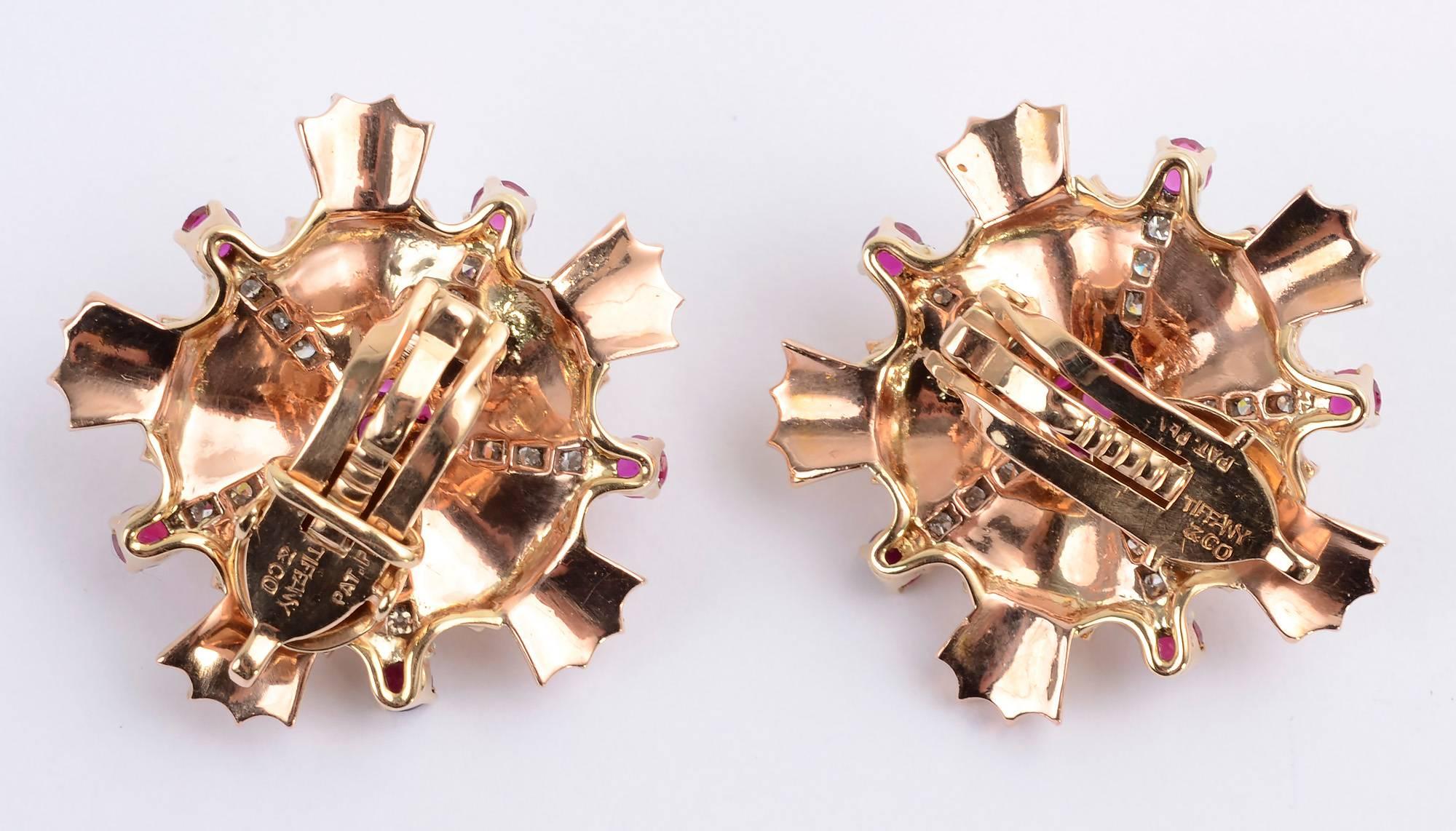 Festive Retro Starburst earrings by Tiffany and Co. They are centered with a cluster of rubies that are continued on five tips. Five rays of diamonds add additional sparkle. Backs are clips. They are 14 karat pink gold.