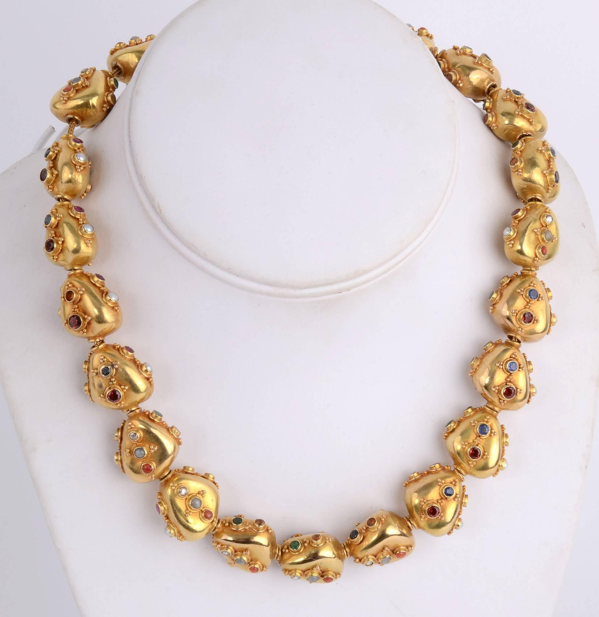Handmade 18 karat necklace of triangular beads studded with round gem  stones that include: sapphire; coral; citrine; moonstone and pearls. Each is collet set and surrounded by tiny gold balls.  The beads are strung on a gold foxtail chain. The