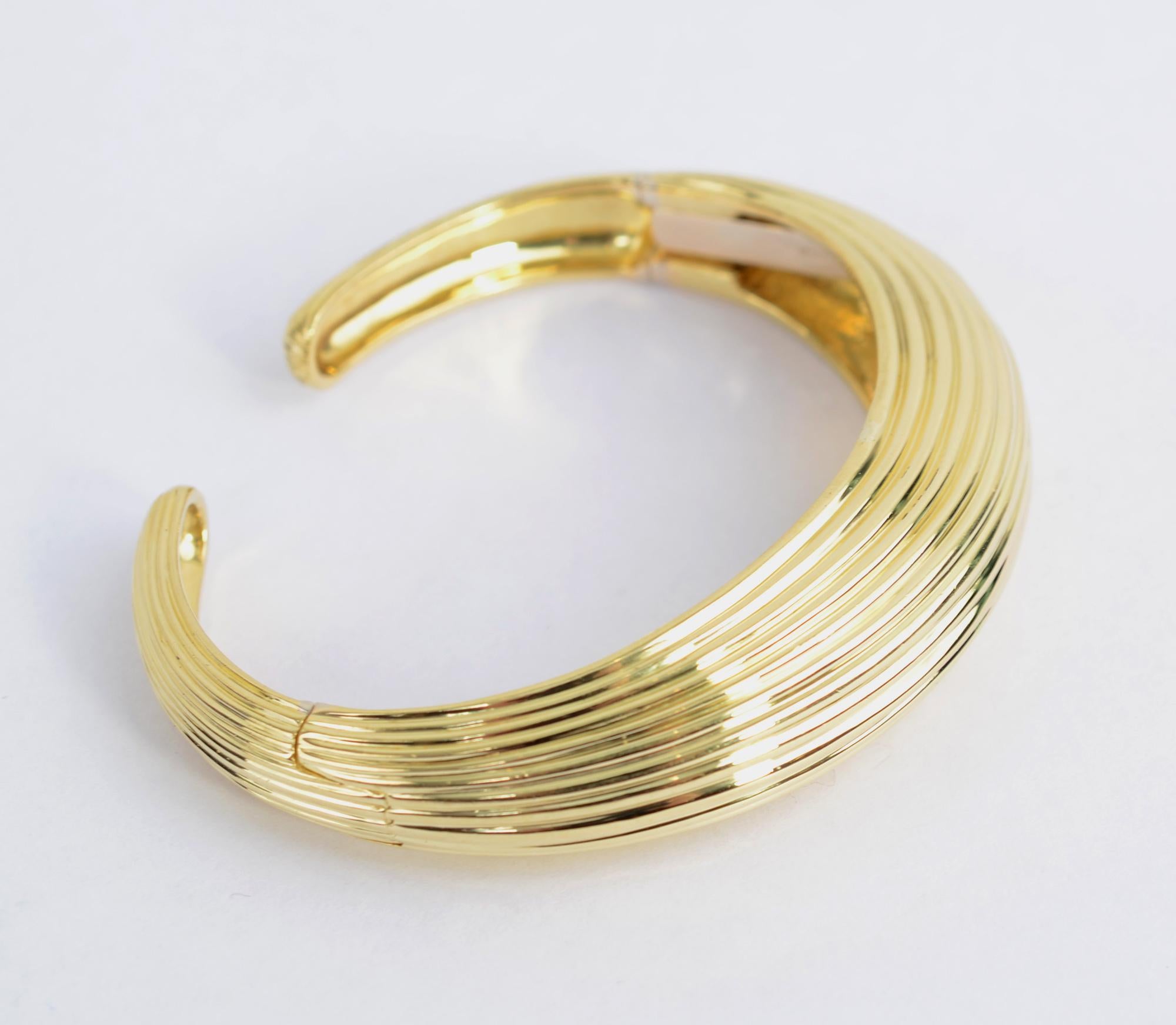 Tiffany 18 karat gold cuff bracelet with ribbed design. The bracelet has two hinges for easy on and off. The front of the bracelet is half an inch tall and 3/4