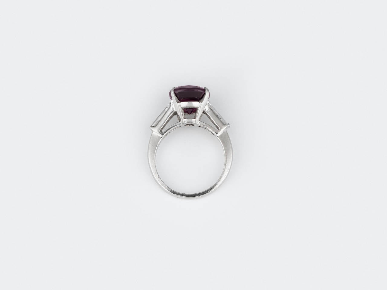 A magnificent, natural spinel commands attention in this stunning ring. Exhibiting a captivating aubergine hue, this rare gem weighs 5.90 carats and is complemented by approximately .35 carats of baguette diamonds. Set in platinum, these lively and