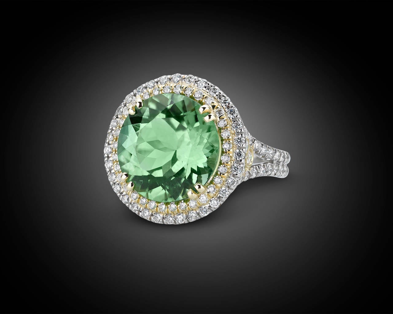 A radiant 8.06-carat Paraiba tourmaline is on display in this exquisite ring. Exhibiting a refreshing and incandescent light green hue, this round-cut gem is joined by a halo of approximately 1.04 total carats of diamonds. Set in platinum and 18k