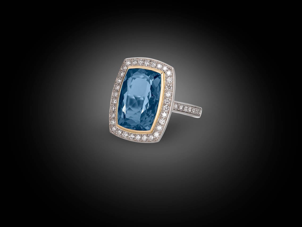 Drama and sophistication mark this eye-catching aquamarine and diamond ring. A truly spectacular stone, the 7.37-carat cushion-cut aquamarine exhibits a radiant and clear ocean-blue hue that is perfectly complemented by a border of 18k yellow gold.