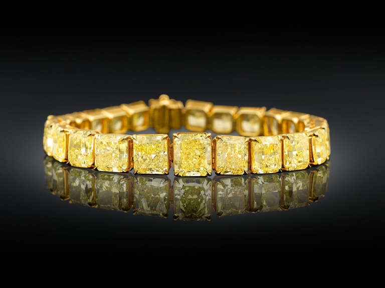 Twenty-five of the most beautiful, perfectly matched Natural Fancy Vivid yellow diamonds, totaling 55.66 carats, create a breathtaking golden glow in this incredible graduated bracelet. Each gem is certified by the GIA to be Natural Fancy Vivid, and
