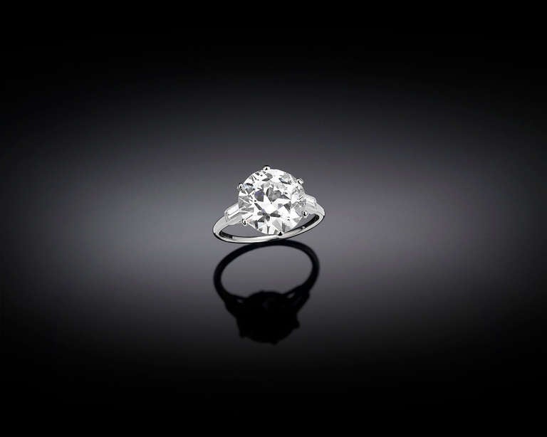 A sparkling diamond exhibits incredible fire in this classic ring by Cartier. Weighing an exceptional 5.15 carats this jewel displays a transitional round cut, which perfectly showcases its J color and VS2 clarity. Two diamond baguettes support this