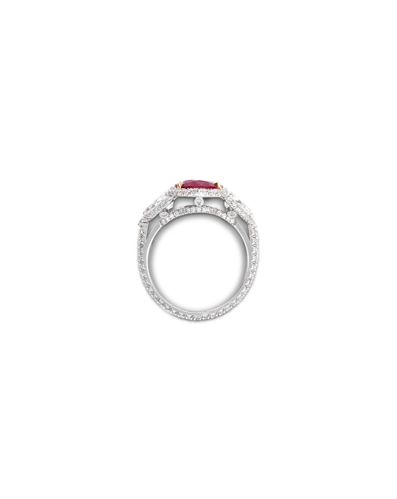 A dazzling 3.02-carat untreated ruby radiates at the center of this mesmerizing stone-led design. Two teardrop shaped diamonds are set, one on each side, of the untreated gemstone, while round diamonds encircle the perimeter and shank, adding to the