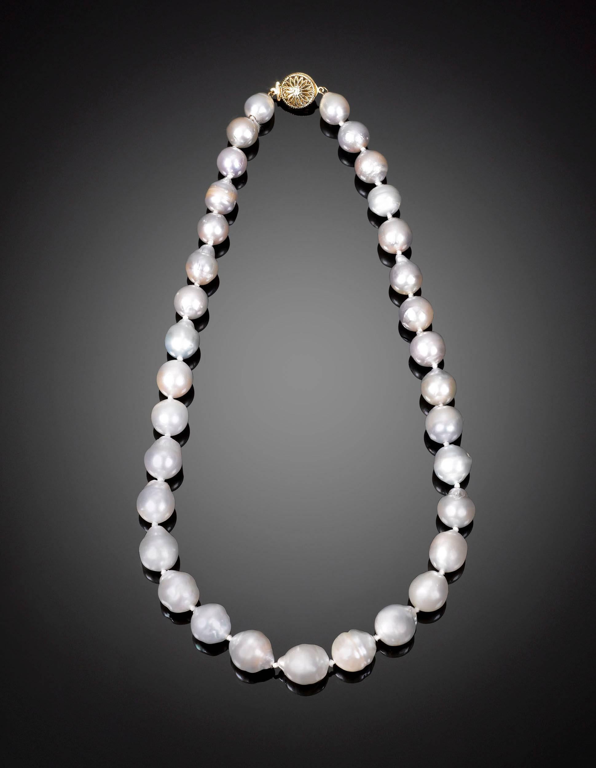 This captivating necklace is comprised of 33 peerless white Baroque South Sea pearls, graduating from 10mm-15mm in size. The pearls are further enhanced by the fine 14K yellow gold filigree clasp that secures the necklace. Harvested from the black