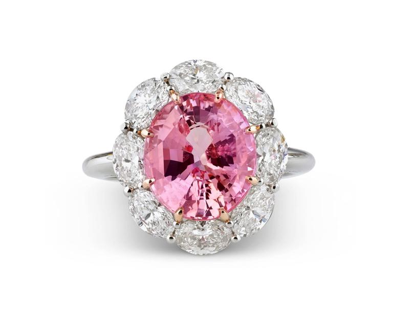 The star of this exquisite ring is a stunning Padparadscha sapphire, the rarest of all sapphires. Weighing 5.61 carats, this intriguing jewel displays the superb pinkish-orange color for which these stones are so coveted. Encircled by approximately