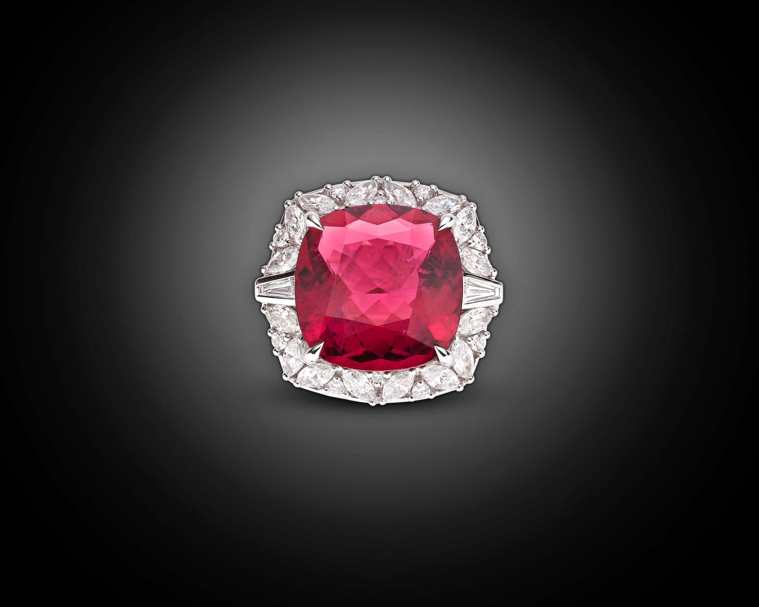 A stunning rubellite tourmaline with a bright, richly saturated crimson hue radiates in this eye-catching cocktail ring. Weighing 9.38 brilliant carats, the gorgeous gemstone is enveloped by a sparkling cushion of diamonds totaling 1.87 carats. The