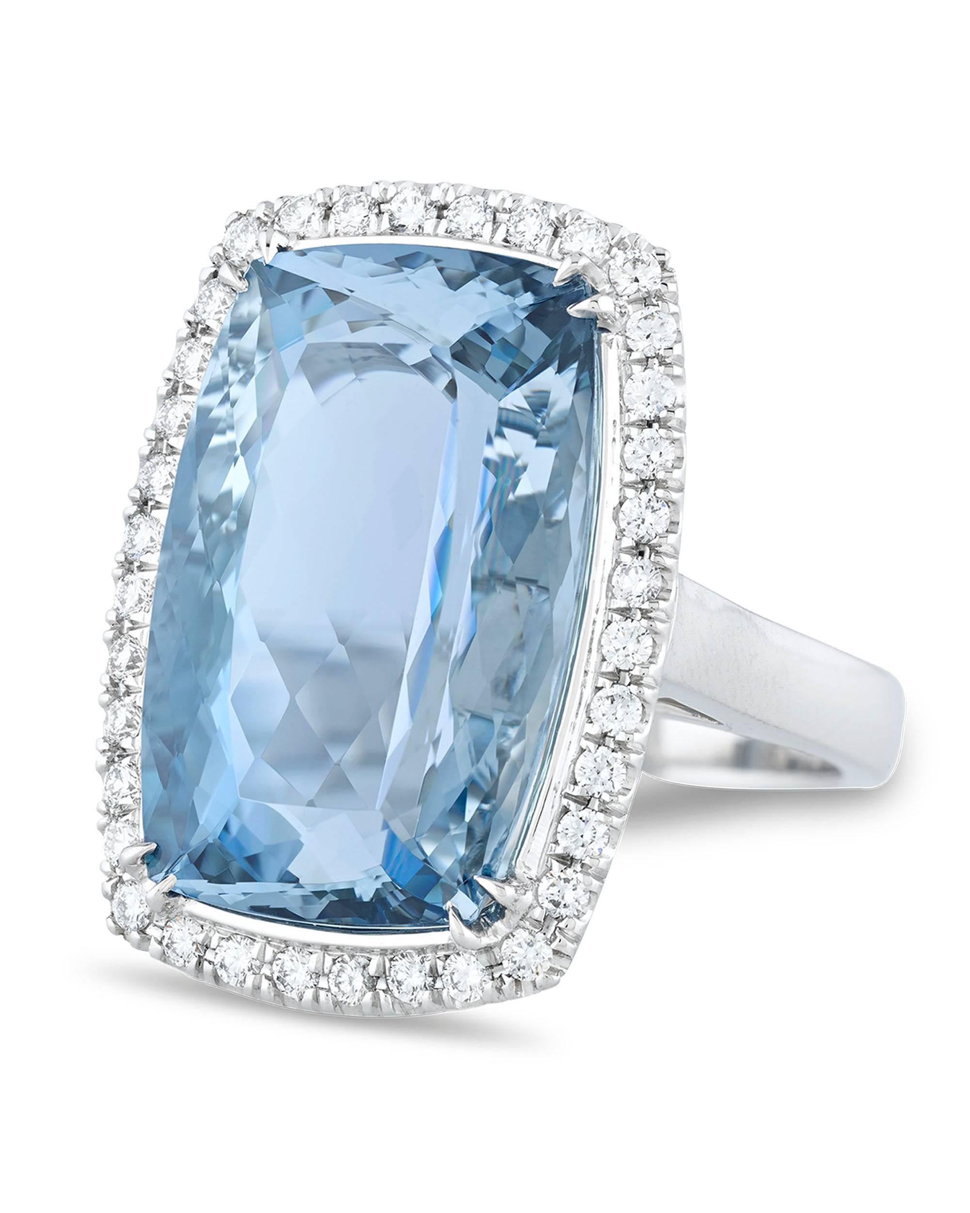 Weighing an impressive 18.52 carats, this cushion-cut aquamarine entrances with its azure hue and fantastic clarity. This wondrous jewel is surrounded by 36 glistening white diamonds totaling 0.53 carats. With a name derived from the Latin for