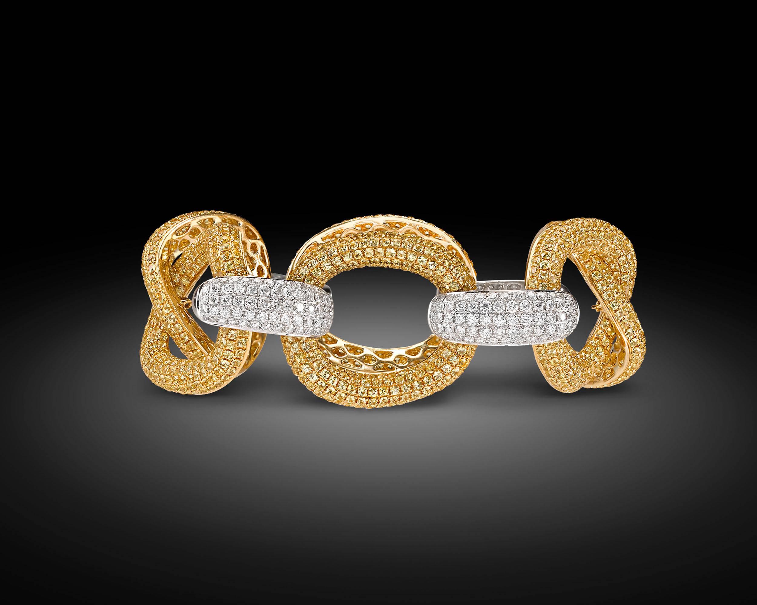 Links adorned by golden yellow sapphires totaling 24.69 carats intertwine with 4.58 total carats of shimmering diamonds in this chic large link bracelet. The enchanting jewels blanket alternating links, creating a dynamic contrast between the