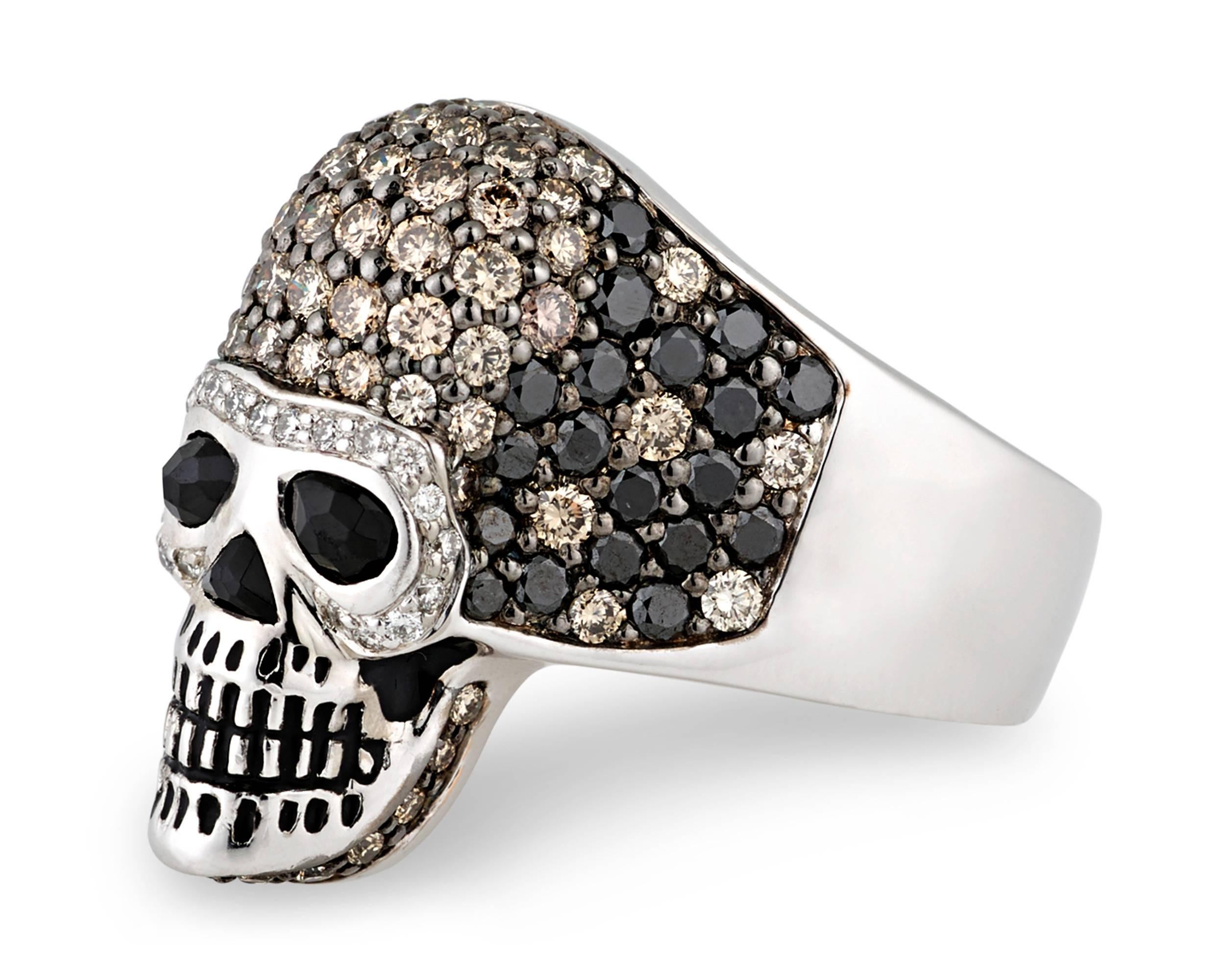 Scintillating diamonds dazzle in this entrancing and edgy skull ring. White diamonds surround the macabre figure's dark spinel eyes, while 1.50 total carats of brown diamonds and 1.29 total carats of black diamonds add bold contrast to the skull's