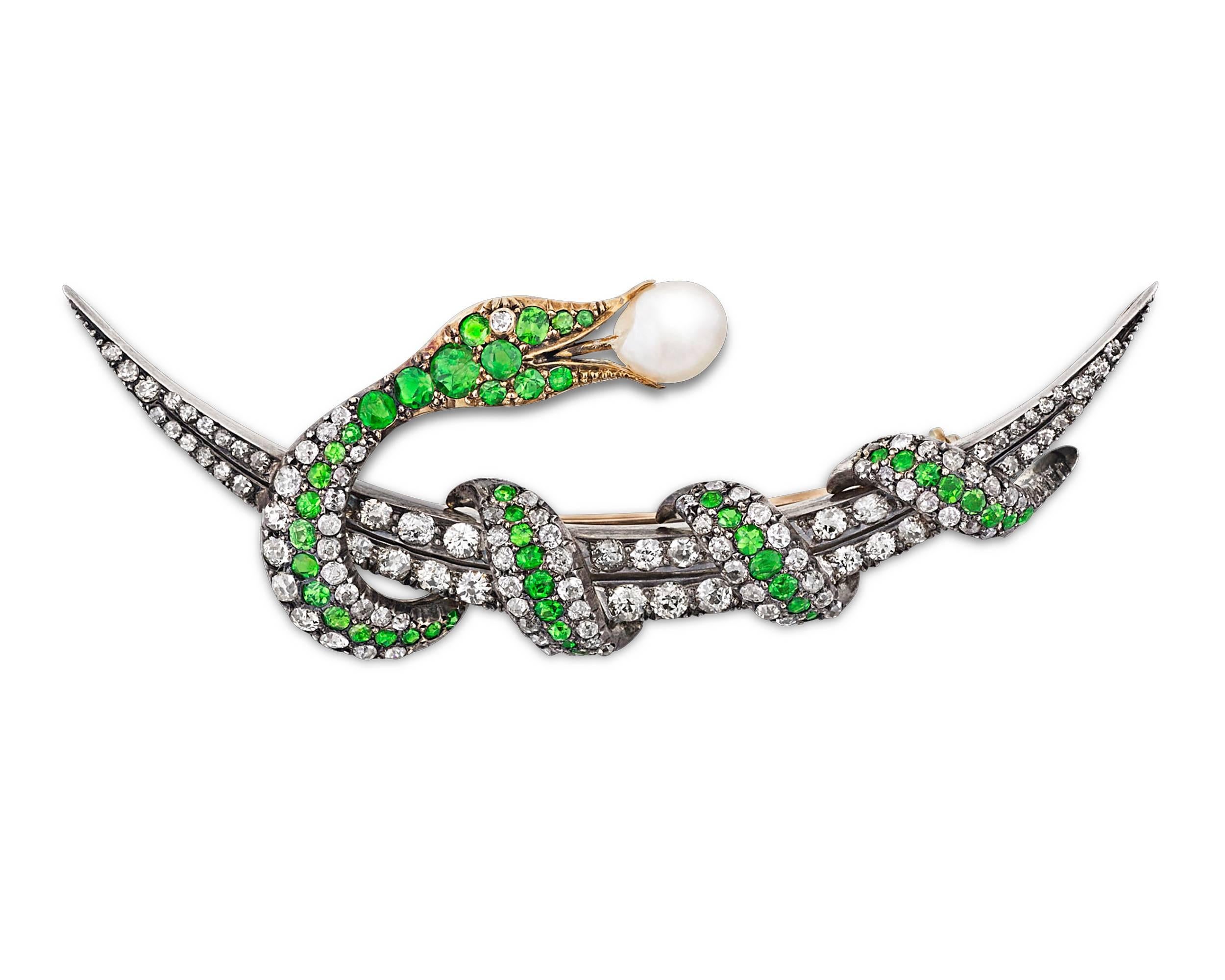 The brilliant green of demantoid garnets accentuate the sleek serpent winding around a crescent moon in this dazzling Victorian brooch. Forty-eight Old Mine and cushion-cut demantoids weighing a total of 2.75 carats highlight snake's body, while 117