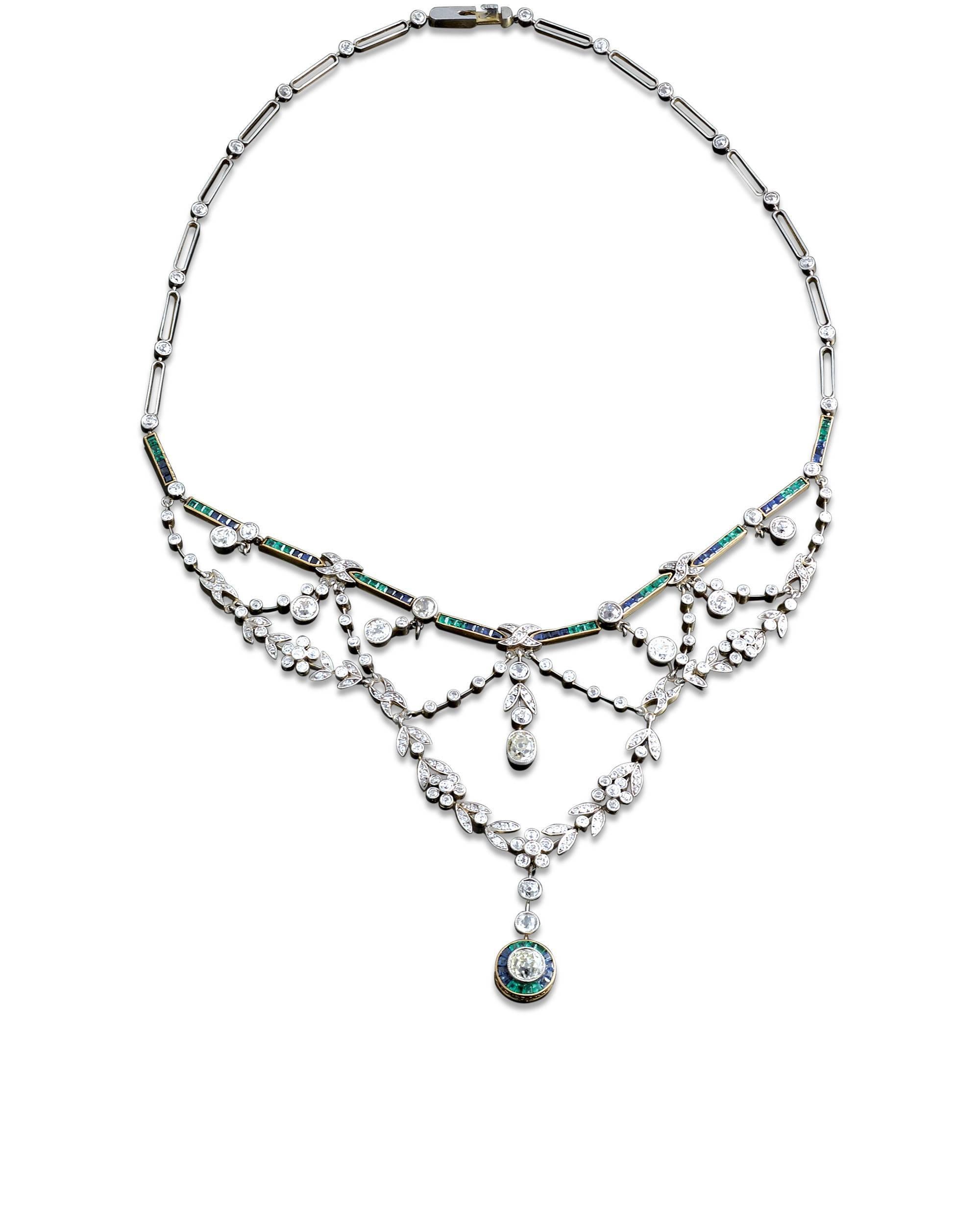 This stunning, classic Edwardian necklace is set with approximately 11.75 carats of shimmering white diamonds, while approximately 2.75 carats of vivid green emeralds and deep blue sapphires provide contrast and color. All gems are set in platinum