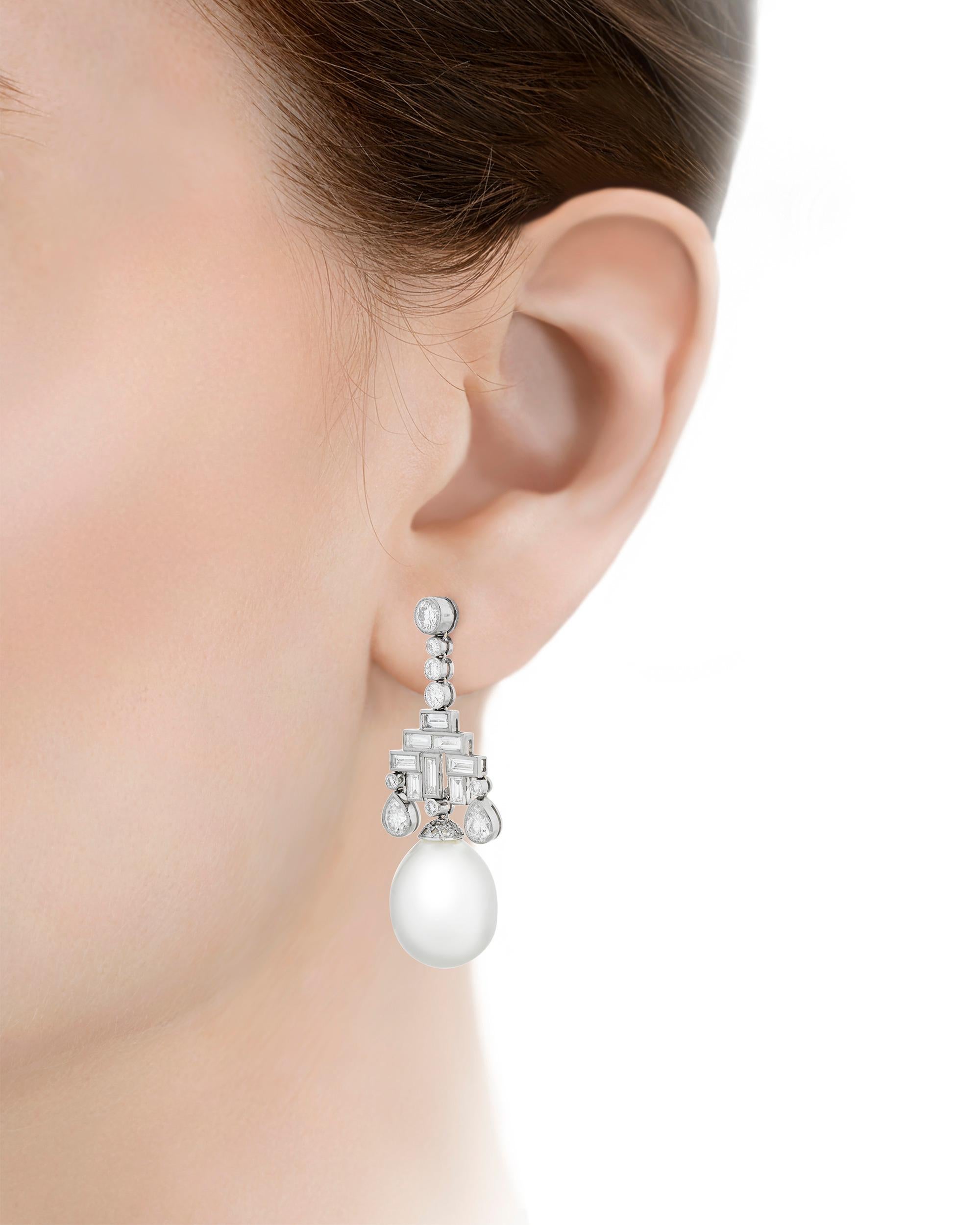 A pair of rare South Sea pearls measuring 18mm x 13.5mm dangle elegantly from these drop earrings. Their lustrous white hue is beautifully complemented by approximately 4.00 total carats of white diamonds in their platinum setting. Handcrafted and