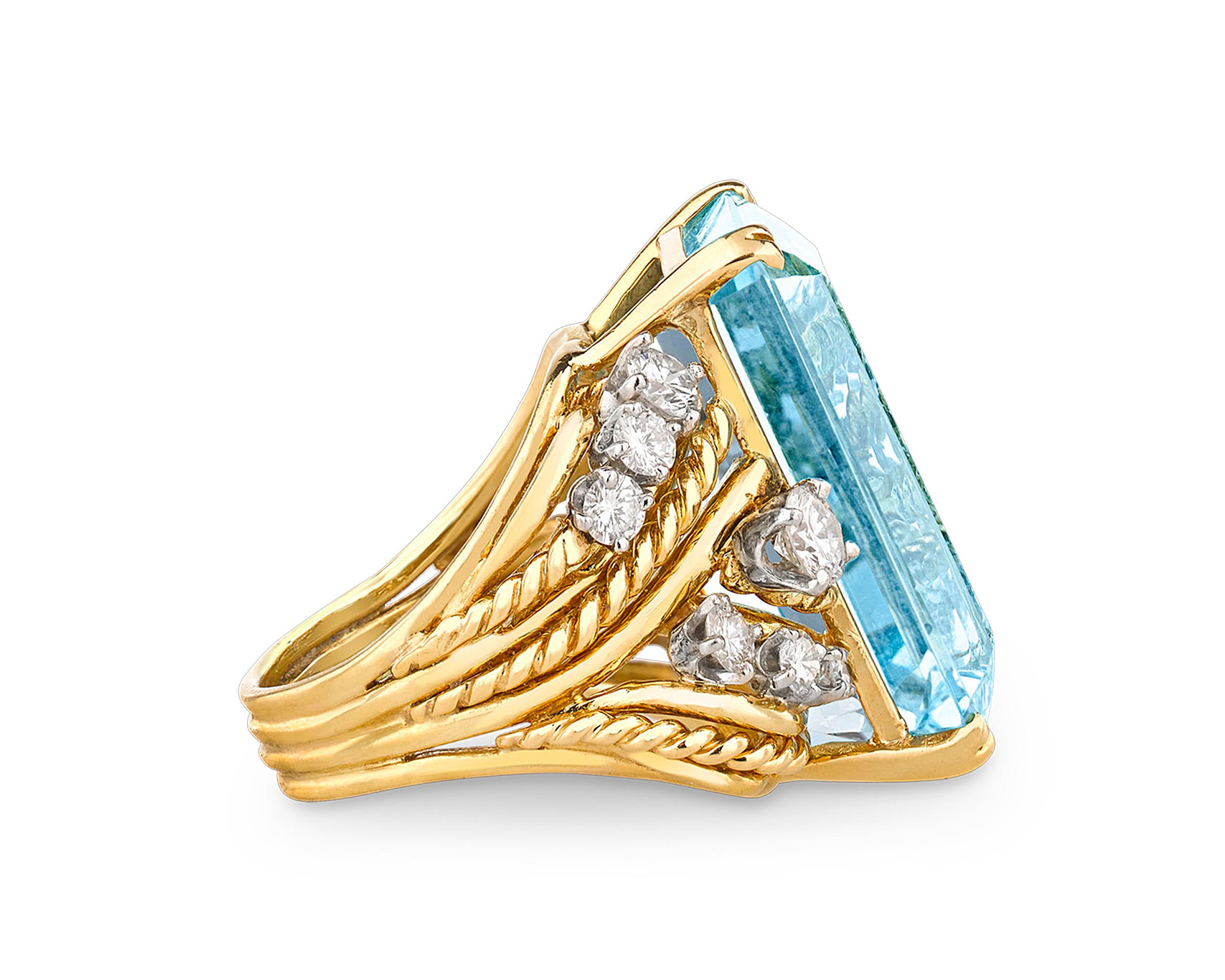 A stunning, pastel blue emerald-cut aquamarine weighing a dazzling 23.30 carats glistens in this eye-catching ring. Displaying a magnificent Mediterranean-blue hue, the stone is stylishly presented in an 18k yellow gold setting with sparkling white