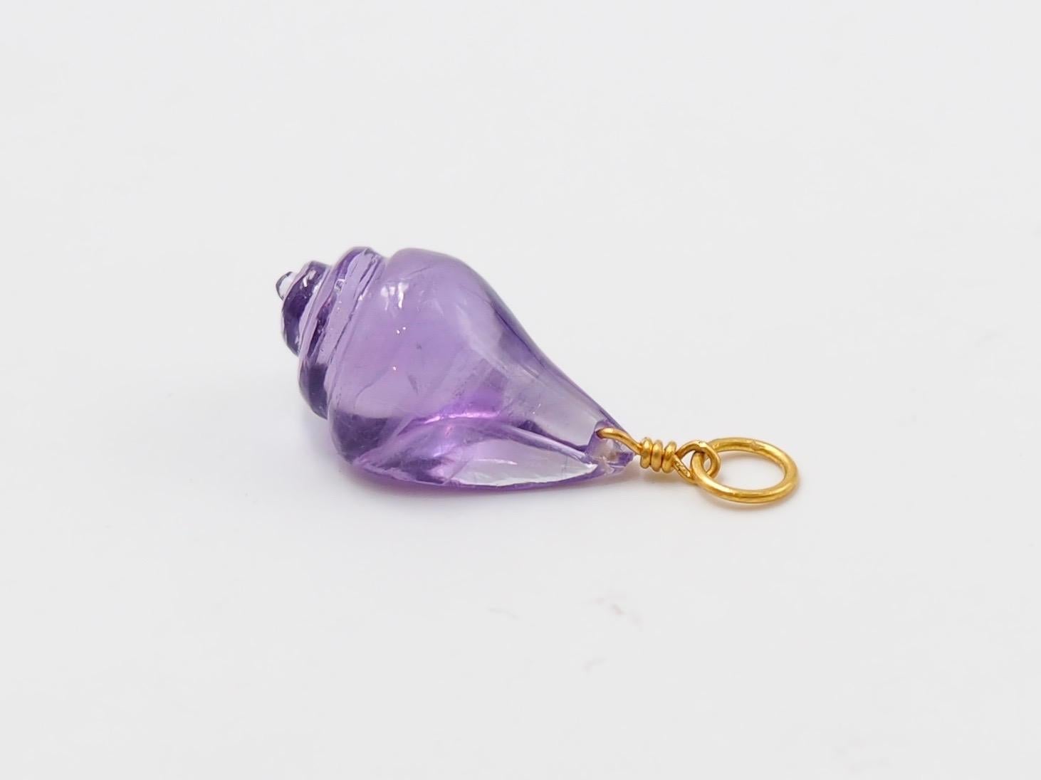 Hand-carved and handmade, this pendant represents a seashell. The stone is simply drilled to allow a fine 22 karat gold wire that is twisted and finishes with a ring. 
3 sizes exist as you can see on the photo.   

Small size in rock crystal,