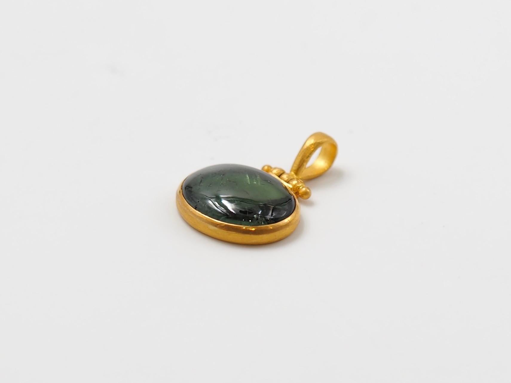 This pendant, by Scrives, is composed of a green tourmaline cabochon of 6 cts. The tourmaline is a deep green colour and exhibit visible natural and typical inclusions. 
The stone is set in a 22 karat gold circle. The top part is a swivel-hook with