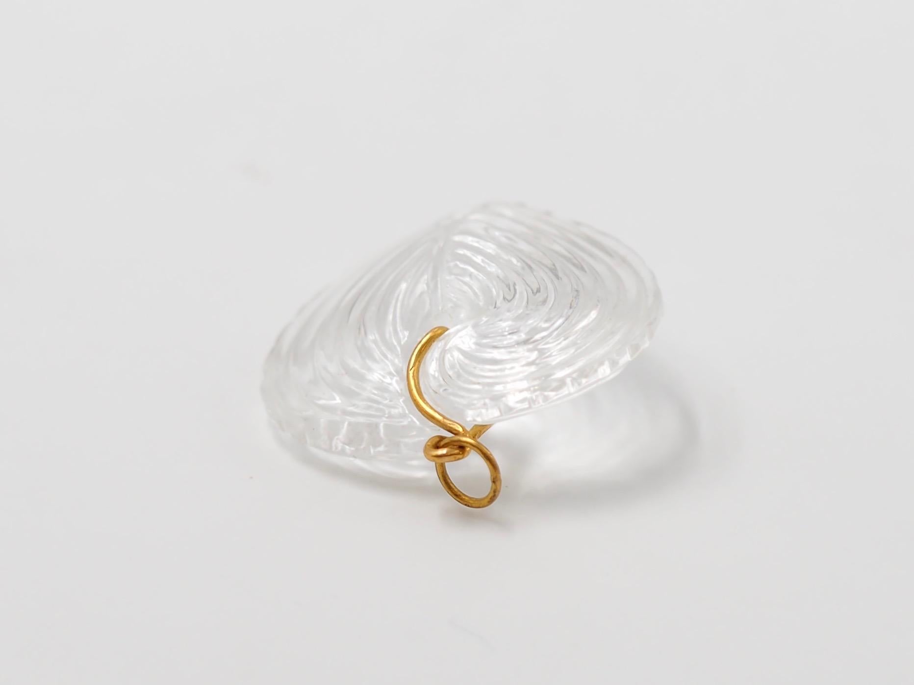 Hand-carved and handmade, this pendant represents a heart seashell in Rock Crystal. The stone is simply drilled to allow a curved 22 karat gold wire that is twisted and finishes with a ring. 

2 sizes exist as you can see on one of the photo. This