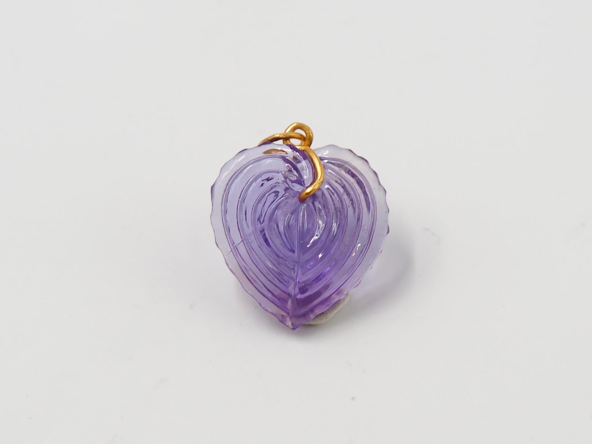 Hand-carved and handmade, this pendant represents a heart seashell in amethyst. The stone is simply drilled to allow a curved 22 karat gold wire that is twisted and finishes with a ring. 

2 sizes exist as you can see on one of the photo. This