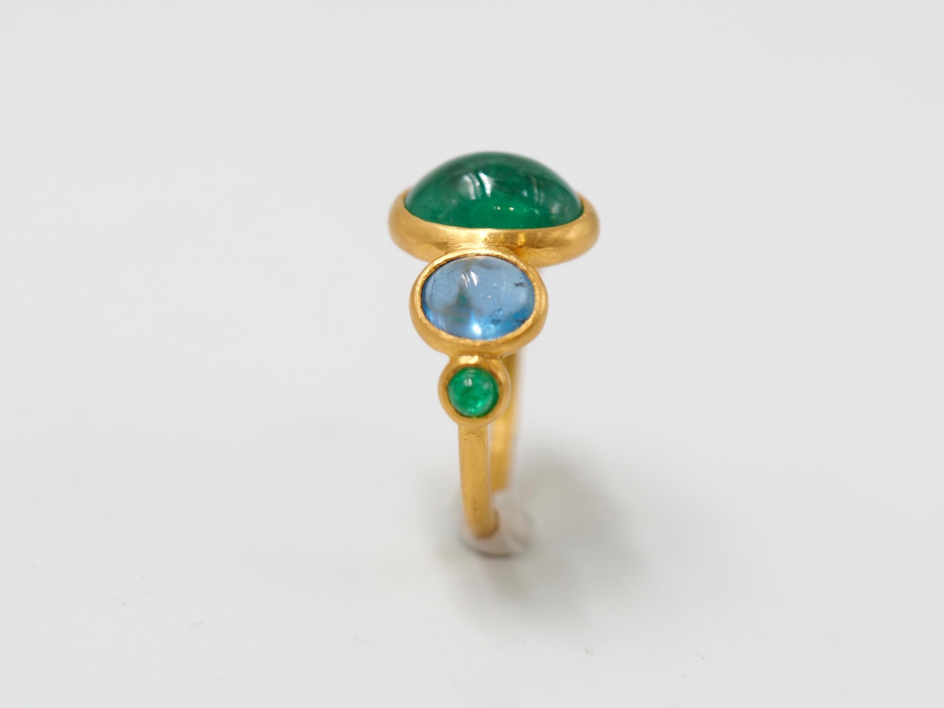 This delicate ring is composed of 5 stones in line: 3 natural emerald cabochons and 2 deep blue natural aquamarine cabochons. The center stone is an emerald of 3.79 cts and the 2 smaller emeralds have a total weight of 0.27cts. The 2 aquamarines