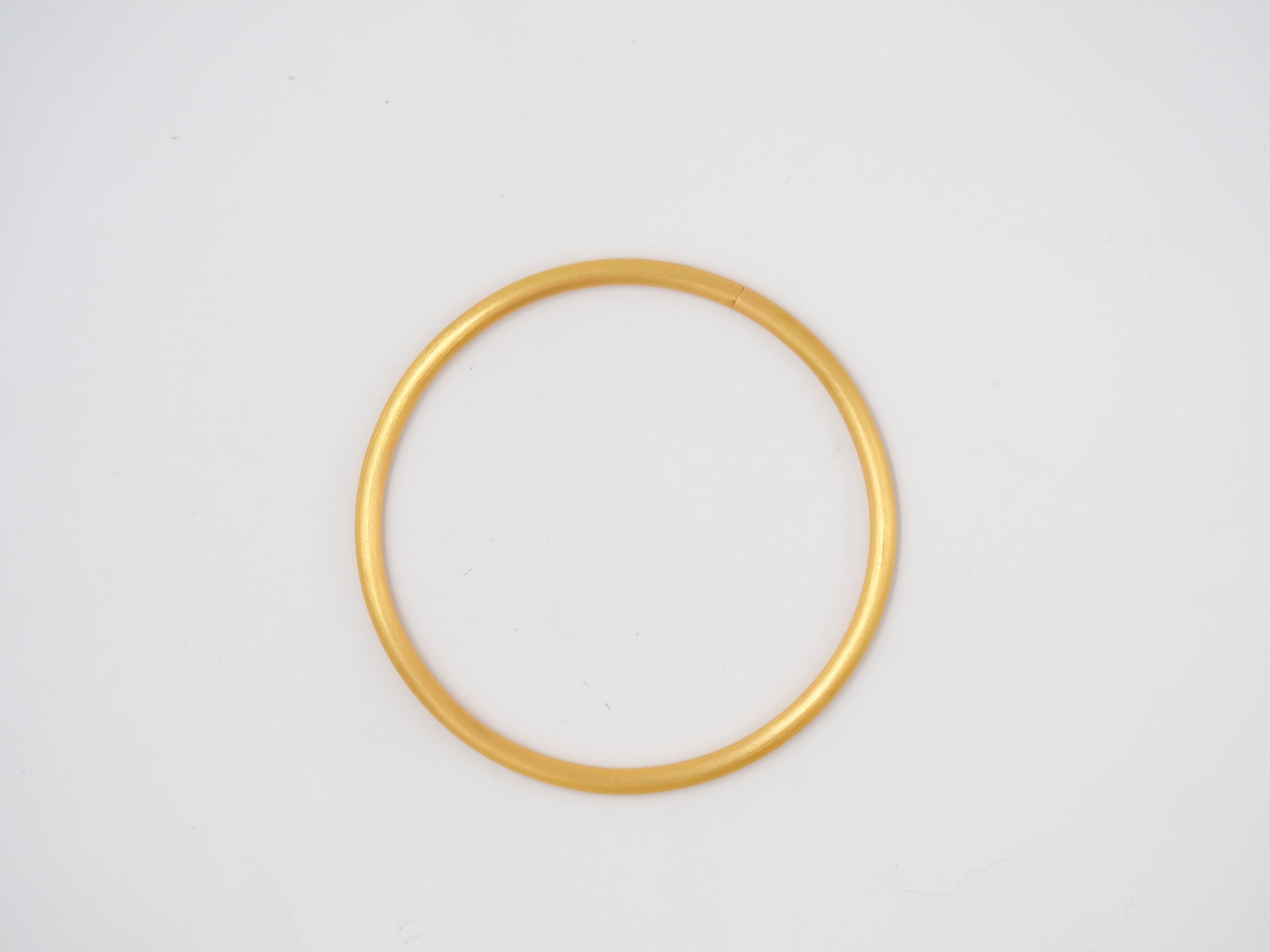 This simple bangle has a round shape and has a gold mat finish. The bangle is handmade in gold 20kt and hollow. 
It is 3mm thick, which allows you to add charms like on the photo! The charms are not included but if you wish to add some, do not