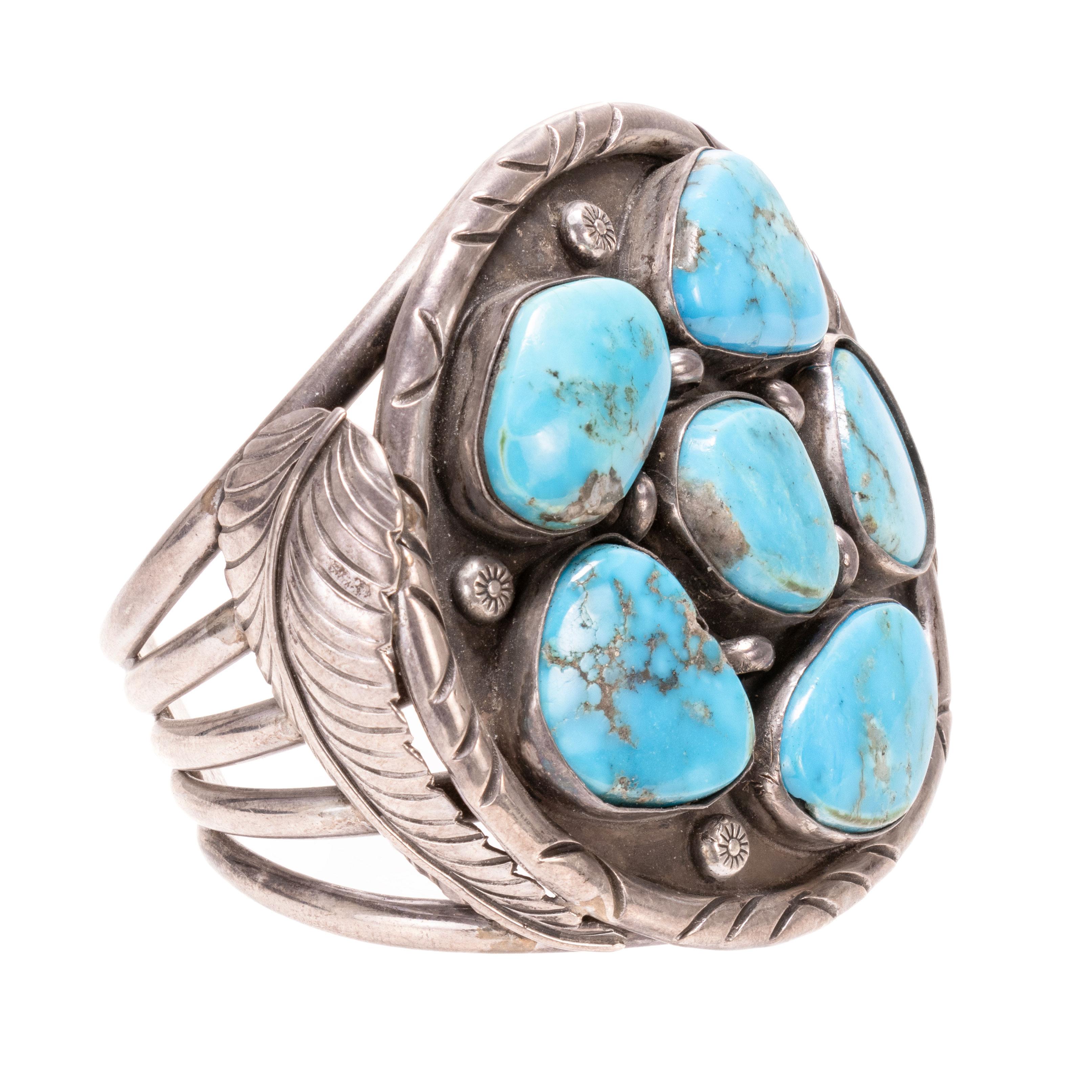 Bracelet manchette en turquoise et argent. Au centre, une boîte ronde contenant six turquoises Kingman et des perles en métal estampé. Encadré par des plumes en argent sterling. Marqué au dos 