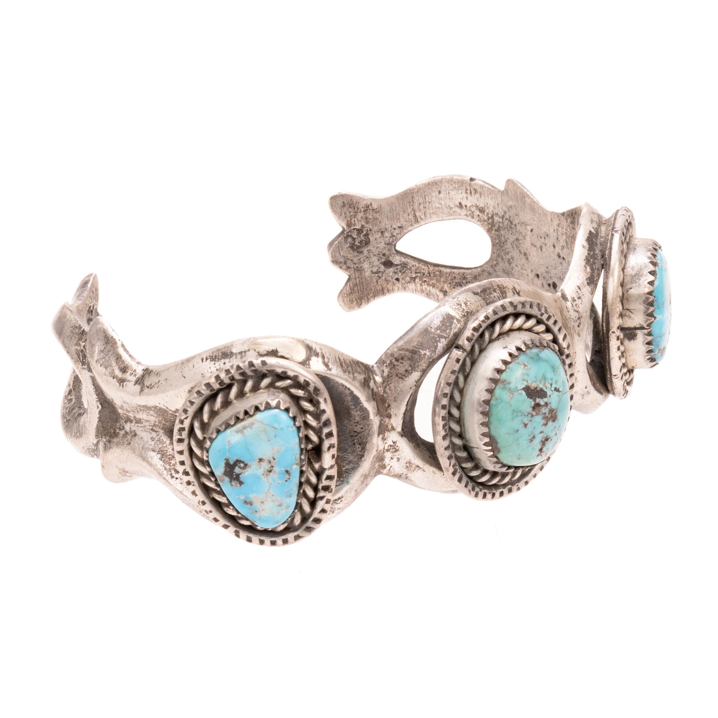 Turquoise and sand cast sterling silver bracelet. Featuring three Kingman turquoise stones set in sand cast cuff, each stone having a twisted rope border. Unmarked. Old Pawn. From the Indian Store in Clovis, New Mexico. Size: 5 1/2