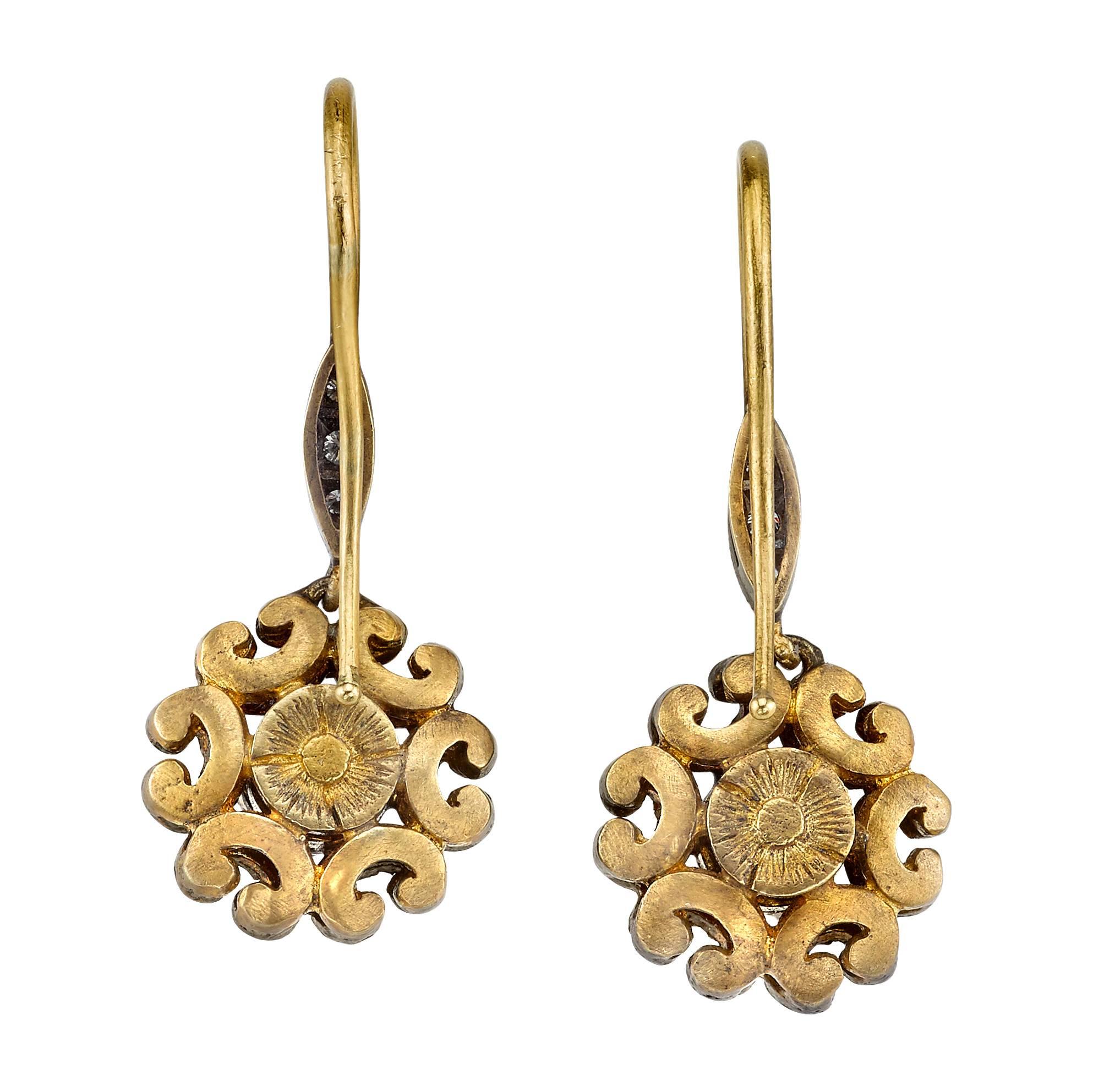 18 Karat Yellow Gold Dangle Earrings with 0.50 CT Rose Cut Diamonds and 0.44 CT Round Brilliant Cut Diamonds, accented with an Antique Silver Patina Finish. These earrings hang at about __ inch in length and are 0.5 inches wide. 

Inspired by the