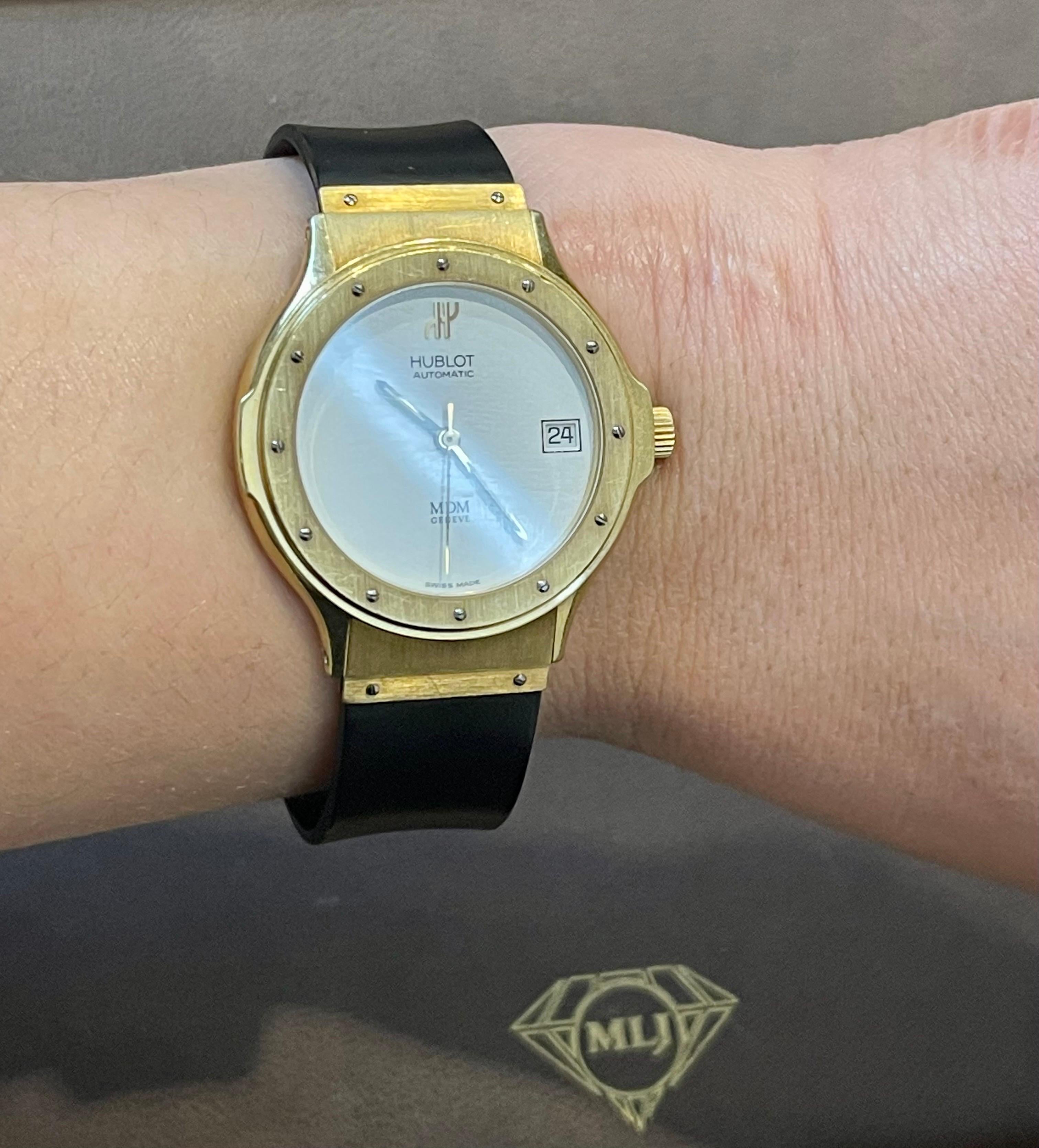 Offered here Unisex Hublot MDM in a 36 mm across case. This watch was made in the 1990s.
Reference 1581.3 indicating an automatic movement model.
The case is 18K gold. 
White dial without the hour markers. Quick set date aperture at 3 o'clock.
The