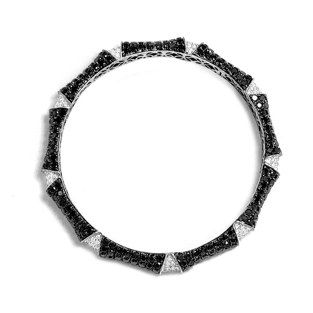 Unique and sleek tuxedo inspired bangle created in 18 karat white gold with black rhodium plating, it features 13.00 carats of exotic black diamonds and 2.10 carats of white diamonds. Approximate diameter is 2 3/8 inches. This beautiful bangle is