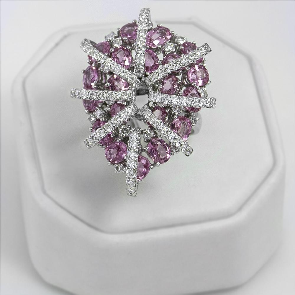 Artist designed pink sapphire and diamond ring featuring 20 beautiful oval pink sapphires totaling 8.75 carats and 2.40 carats of dazzling diamonds set in 18 karat white gold. This magnificent ring is available in stock. It is in size 7 and if