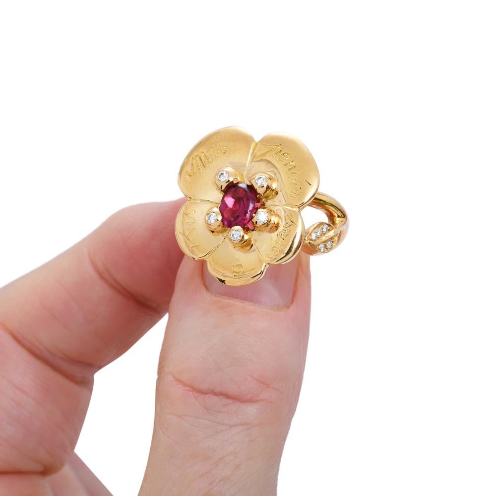 Limited edition of a pansy ring in yellow 750/1000 gold (18K)  by Sylvie Corbelin.
On the pansy  is set a garnet and aroud is carved a french phrase 