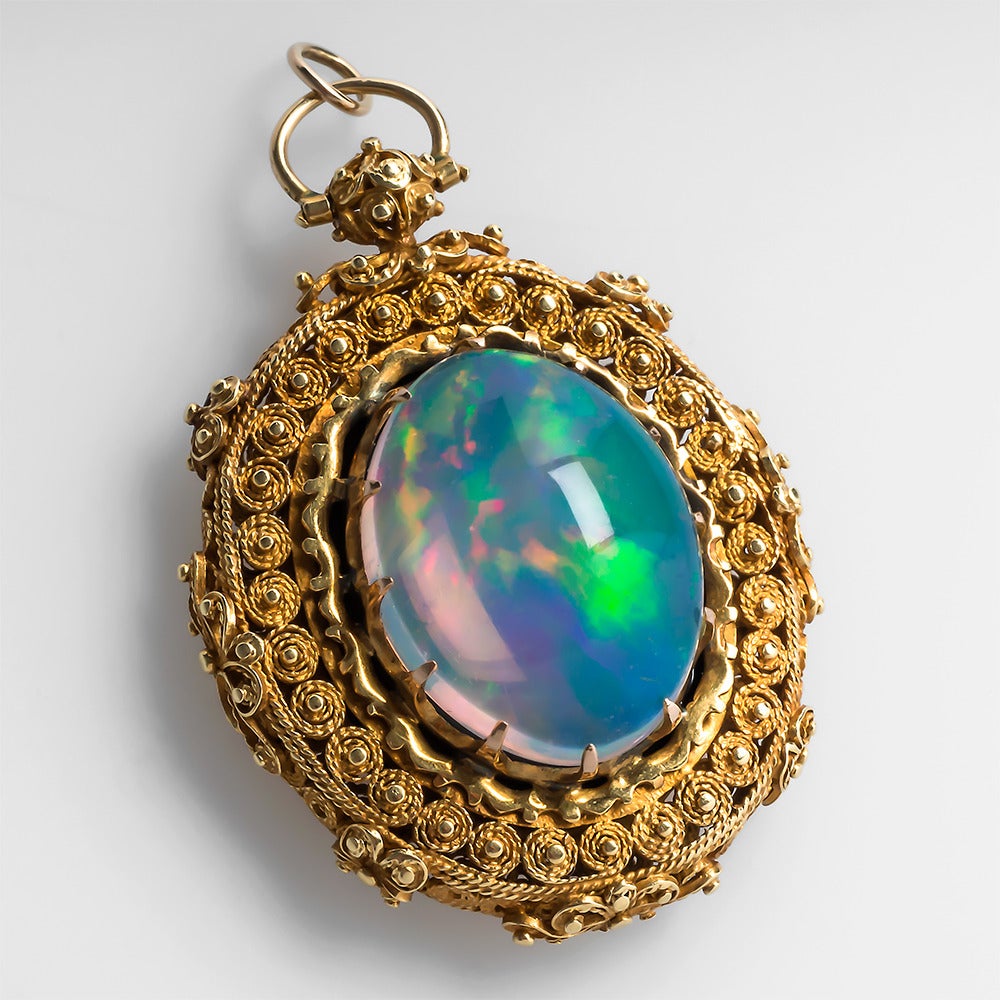 This locket pendant was crafted in the Late Victorian Era and features a magnificent jelly opal crystal surrounded by a very detailed ornate 14k yellow gold setting. The back of the pendant has a removable frame that can hold a photo but currently