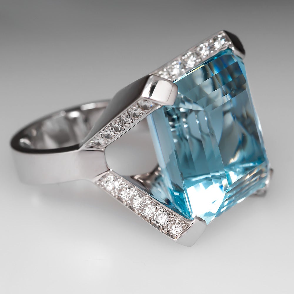This aquamarine cocktail ring is centered with a massive 28 carat emerald cut natural aquamarine gemstone. The stone sits high above the finger and is set with four diamond encrusted wide prongs. The ring is crafted of heavy solid 18k white gold and