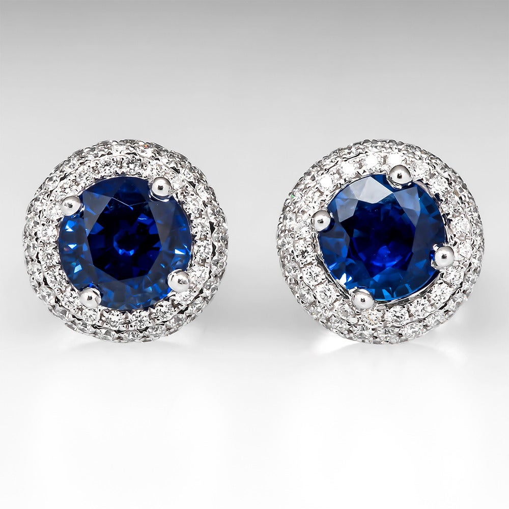 This is a stunning pair of Spark sapphire and diamond halo stud earrings. The pair of round natural blue sapphires are each in a 4 prong setting surrounded by three rows of 68 round brilliant cut natural diamonds. The earrings are well crafted in