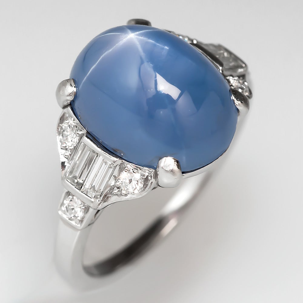 The antique 1930's star sapphire ring features an 8.54 carat oval cabochon cut natural star sapphire. This star sapphire has a centered strong 6-ray star with very good movement. The sapphire is centered between 2 geometric shoulders set with