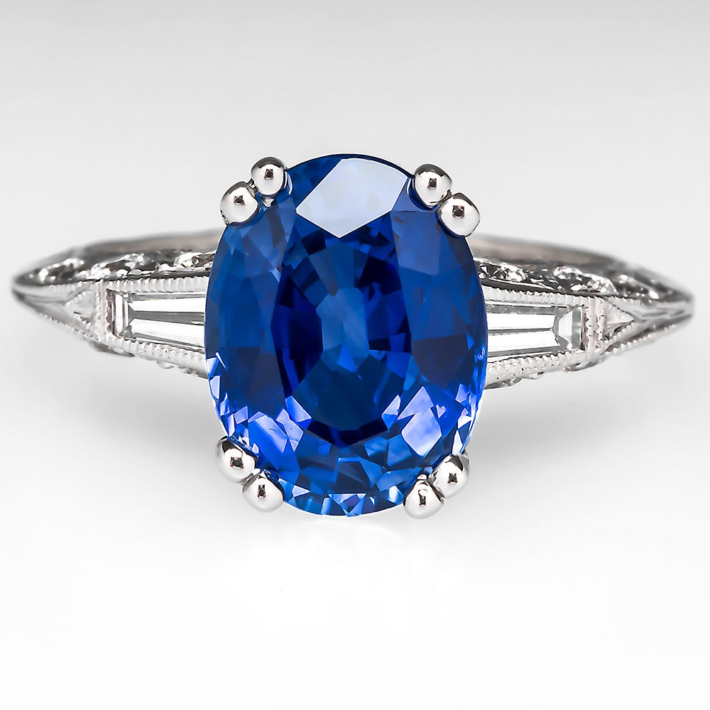 This Tacori sapphire engagement ring is out of this world. It is centered with a breathtaking oval cut 4.45 carat natural blue sapphire that is a medium dark violetish blue color with strong saturation and gorgeous light return. The stone sits atop