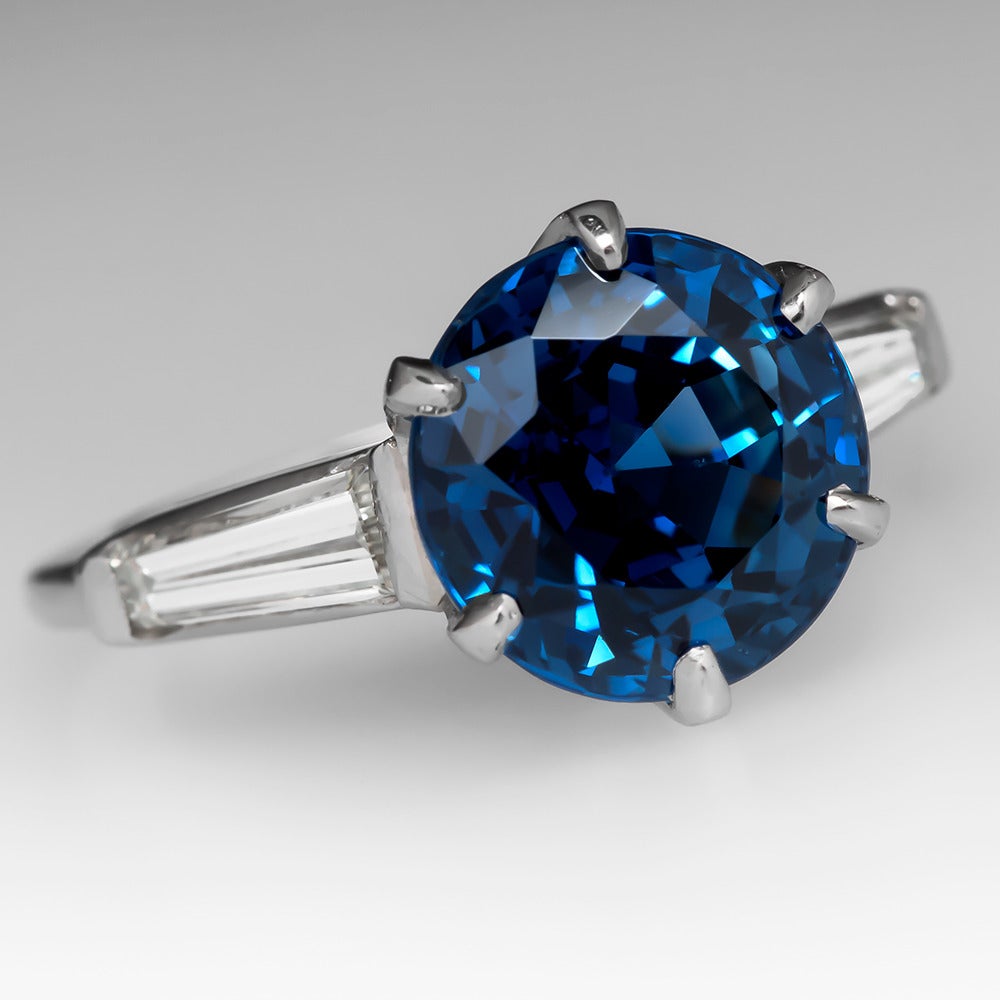 This magnificent blue sapphire engagement ring features a stunning 5.76 carat round cut natural sapphire with tapered baguette diamond accents. The diamonds grade g-h/vvs2-vs1 and total .54 carats. The sapphire is out of this world featuring a