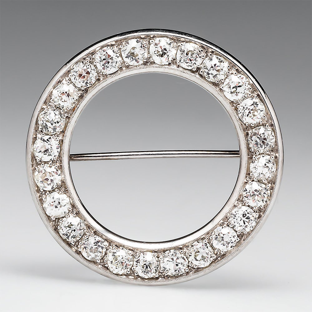 This classic Art Deco diamond circle brooch pin features a total of 24 Old European cut sparkling diamonds. The handmade brooch is finished with milgrain edging and is crafted of solid platinum. This brooch is in very good condition.