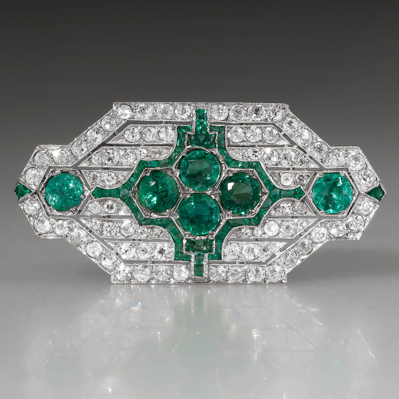 This amazing Art Deco antique brooch pin is crafted of solid platinum and features natural emeralds and diamonds. The emeralds are gorgeous with strong saturation and a slightly bluish green hue. The emeralds total a bit over 4.5 carats and the
