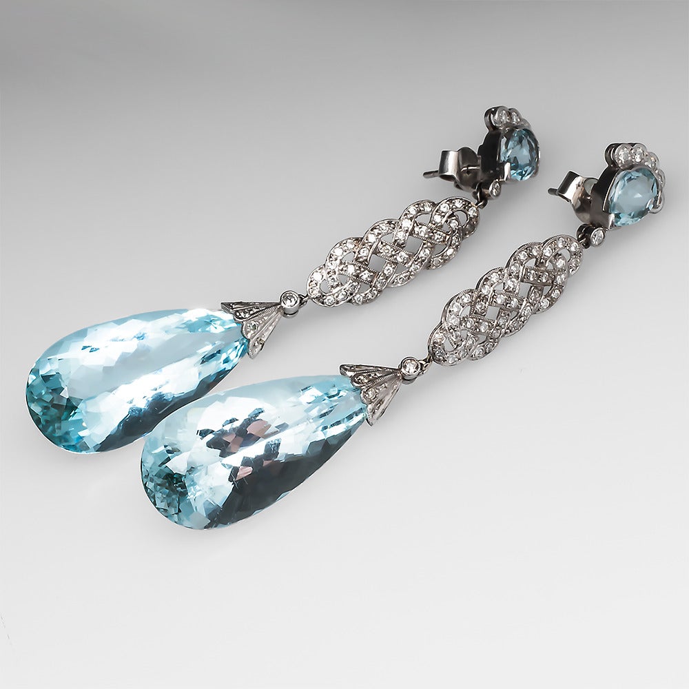 These striking estate chandelier earrings are crafted of solid platinum and feature briolette cut natural aquamarine gemstones accented by genuine natural diamonds and bezel set aquamarines. These earrings hang 3 inches and are ready for any Red